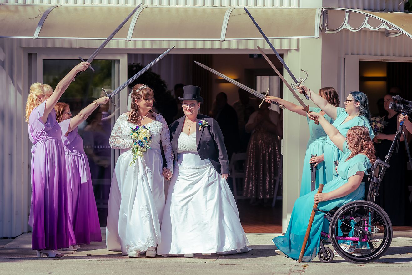 Wedding party members in turquoise and purple gowns stand together during a formal celebration.