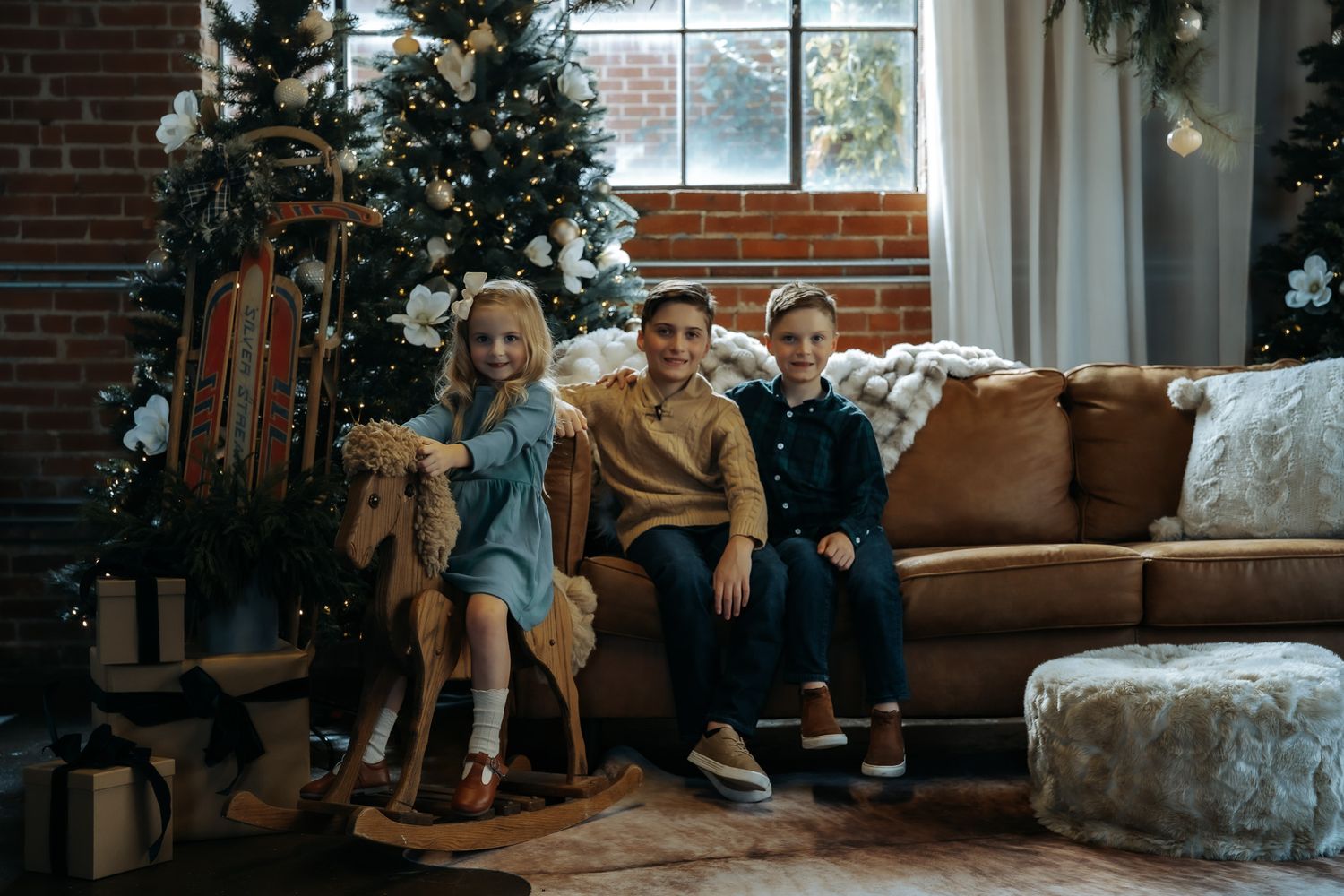 A family relaxes and spends quality time together on a brown leather couch in a cozy brick-walled living room.