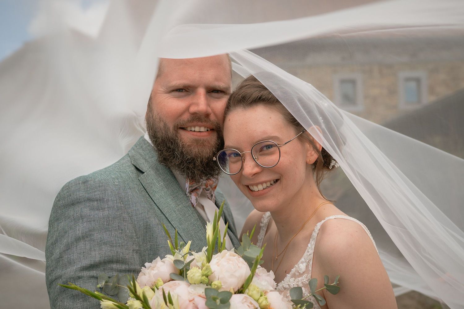 A romantic wedding couple shares intimate moments in an outdoor setting wearing gray and white attire.