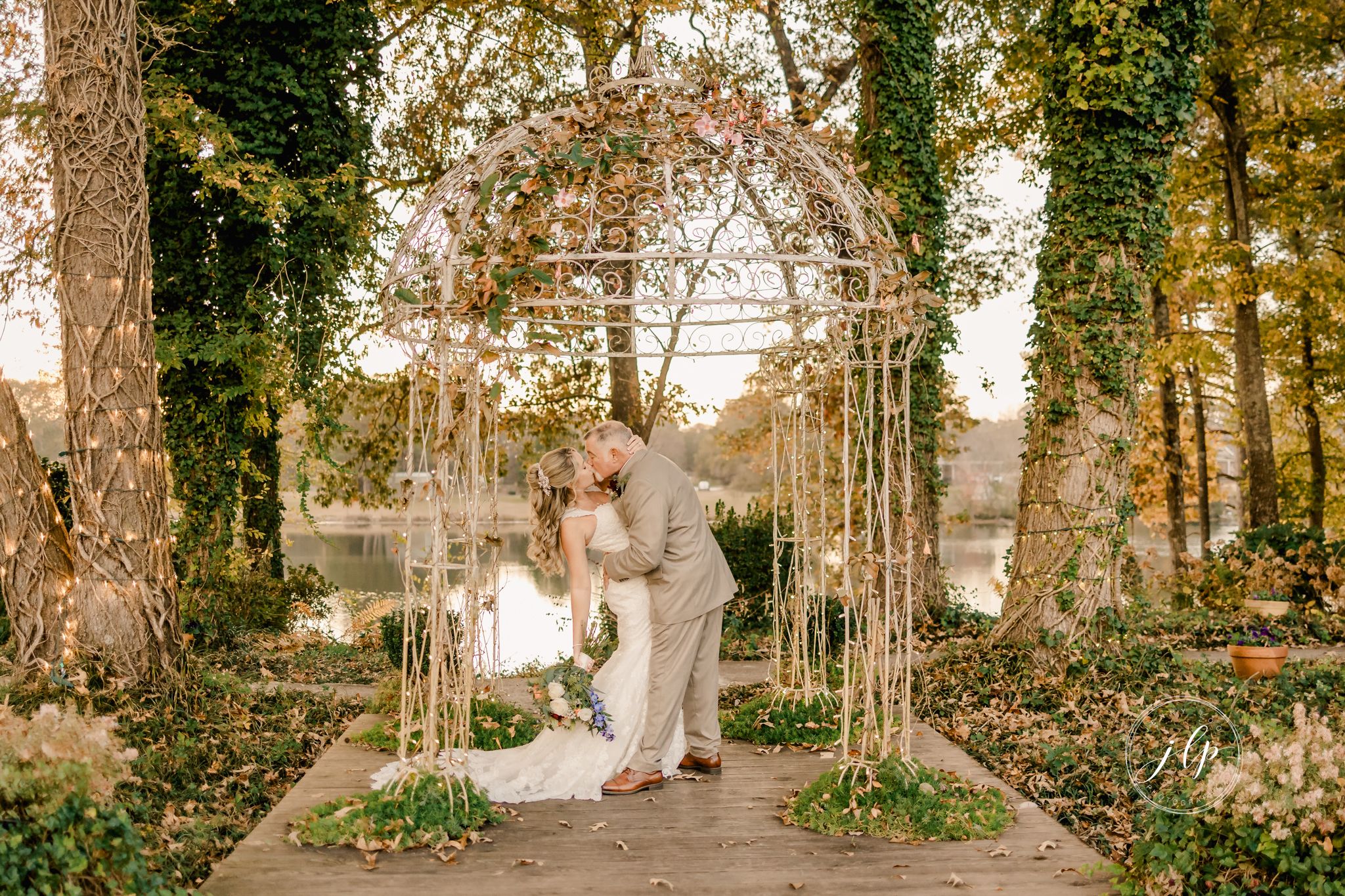 Elegant couple shares romantic moments in a sunlit forest setting with autumn foliage and tall trees.