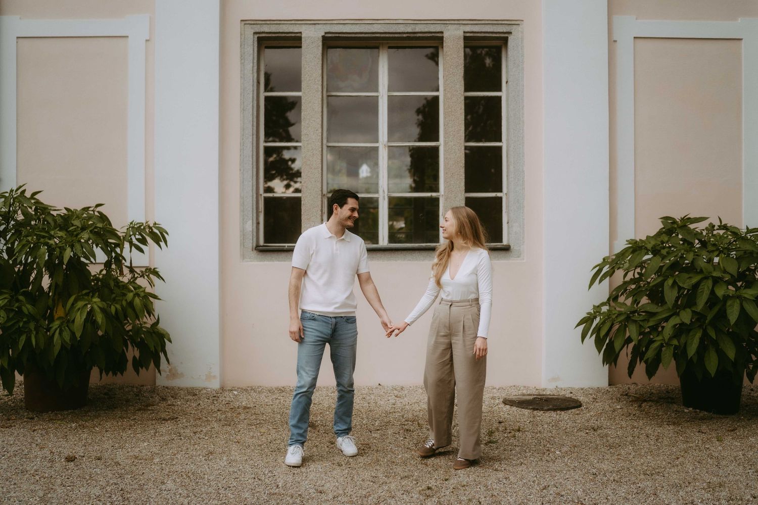 A couple walking together outside a white building with classic windows.