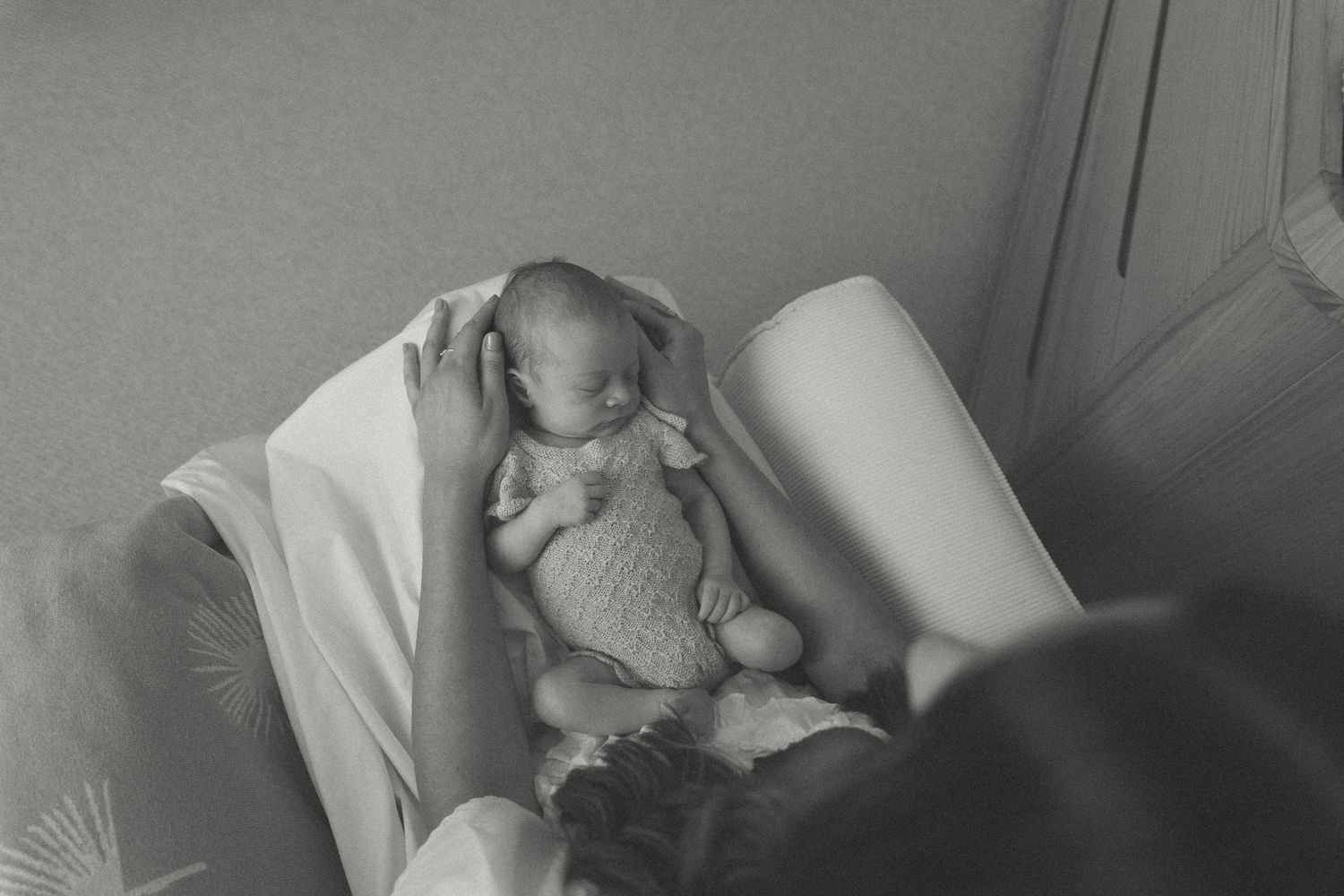 Medical professionals examine and provide care to an infant patient lying on an examination table.