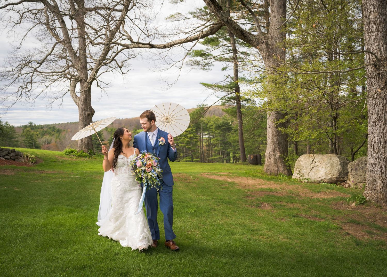 Newlyweds share an intimate moment outdoors with autumn foliage and rustic architecture in background.