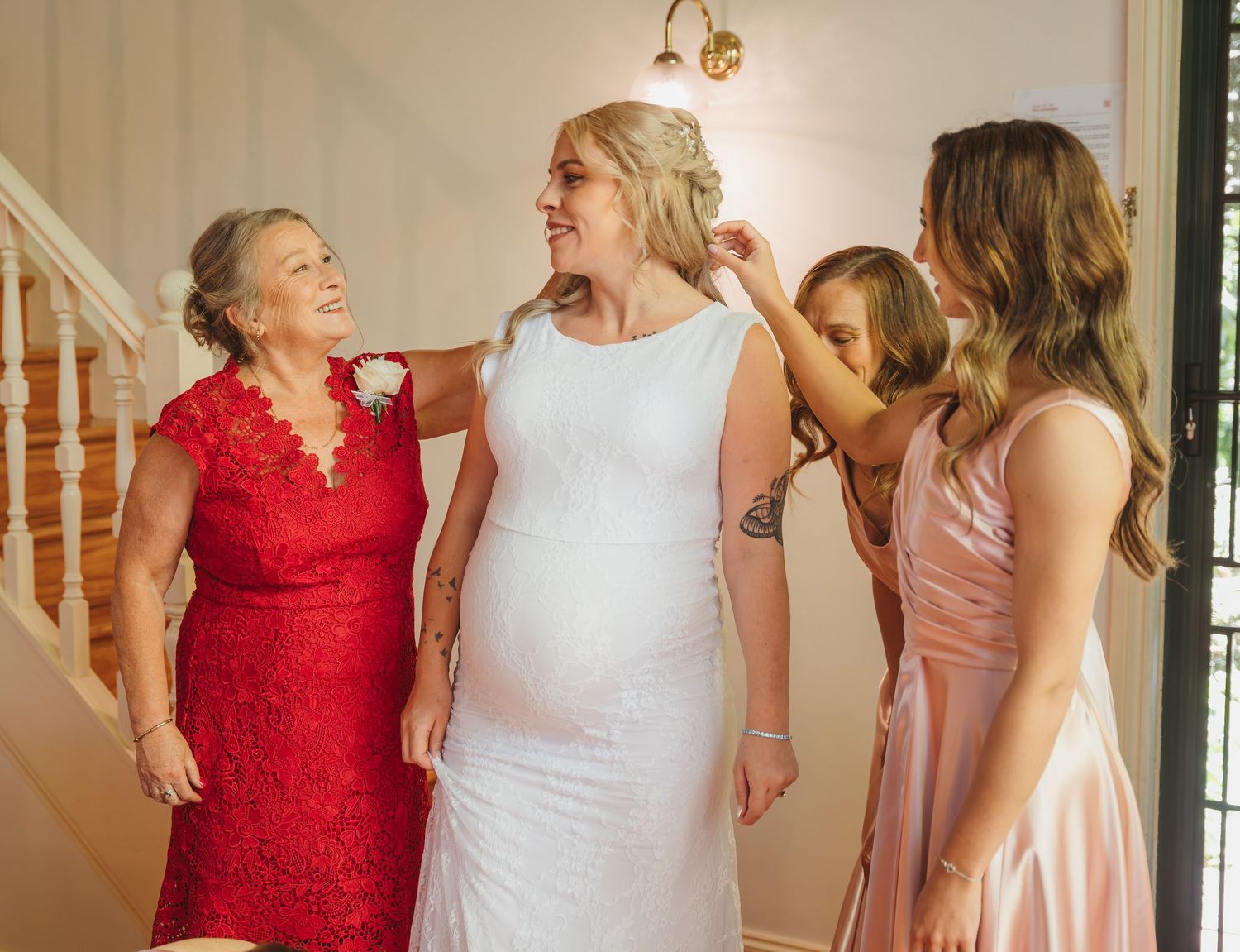 Wedding party getting dressed in pink and red dresses share excited reactions and joyful moments together.