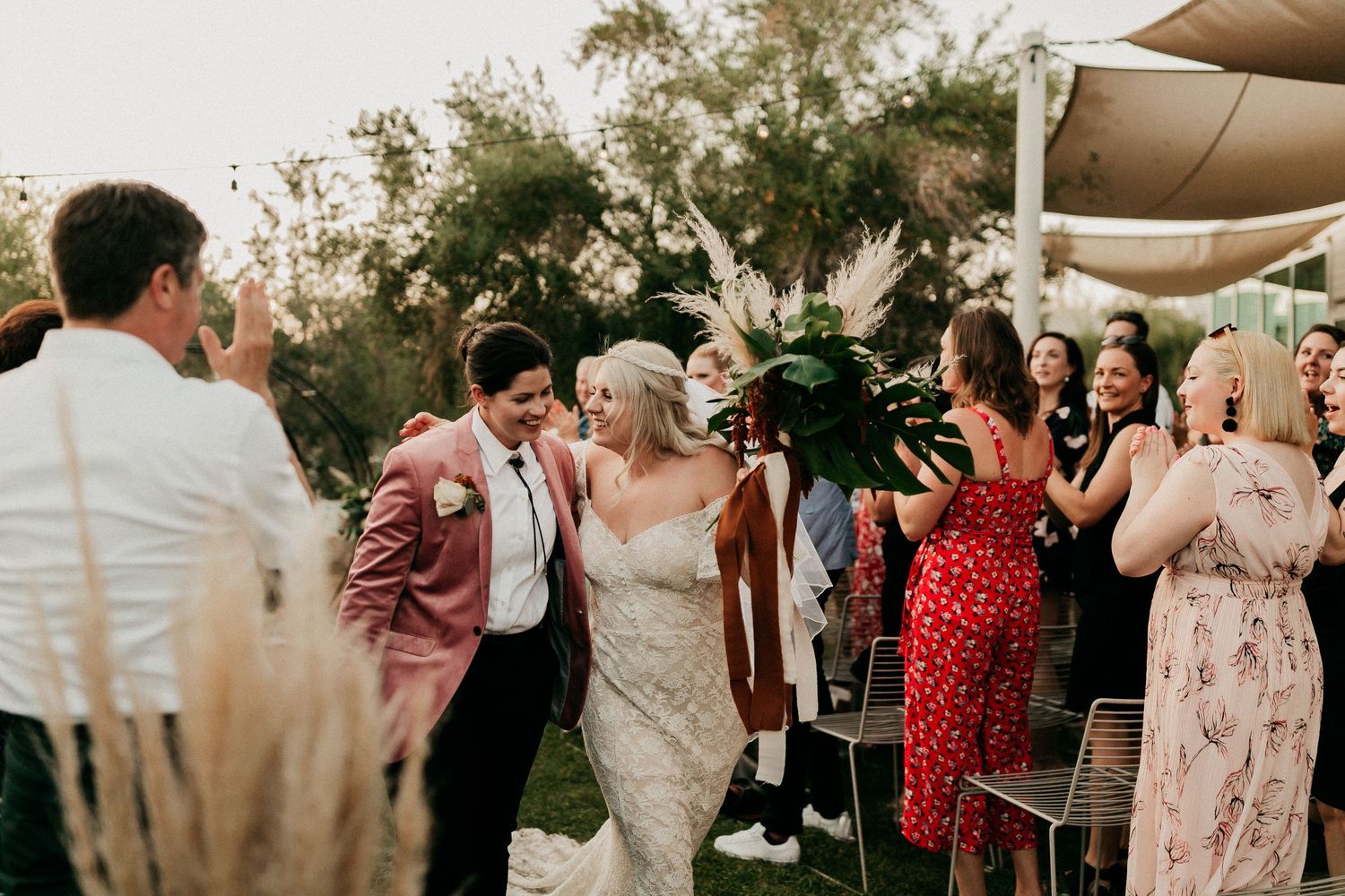 Outdoor wedding reception under canopy tents with guests mingling during golden hour.