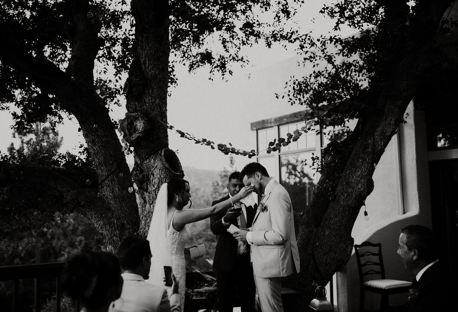 Newlyweds pose in front of trees at a scenic outdoor wedding ceremony location at sunset.
