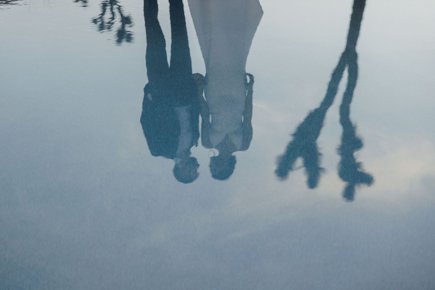 Artistic water reflection of bride and groom silhouettes creating a dreamy wedding portrait.