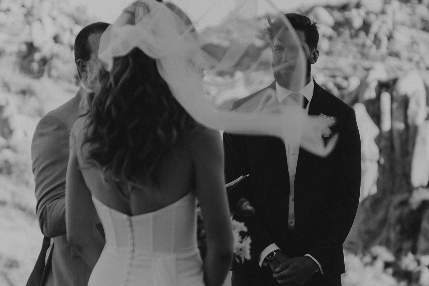 A black and white wedding ceremony photograph showing the couple at the altar with flowing veil and elegant attire.