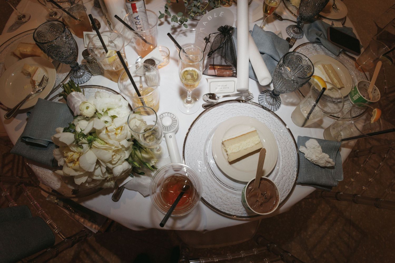 Aerial view of elegantly set wedding reception table with white floral centerpiece and china.