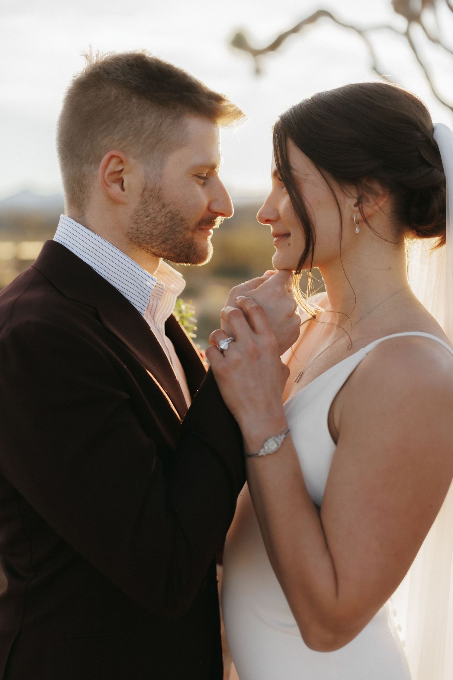 Bride and groom share intimate romantic moment at golden hour during outdoor desert wedding.