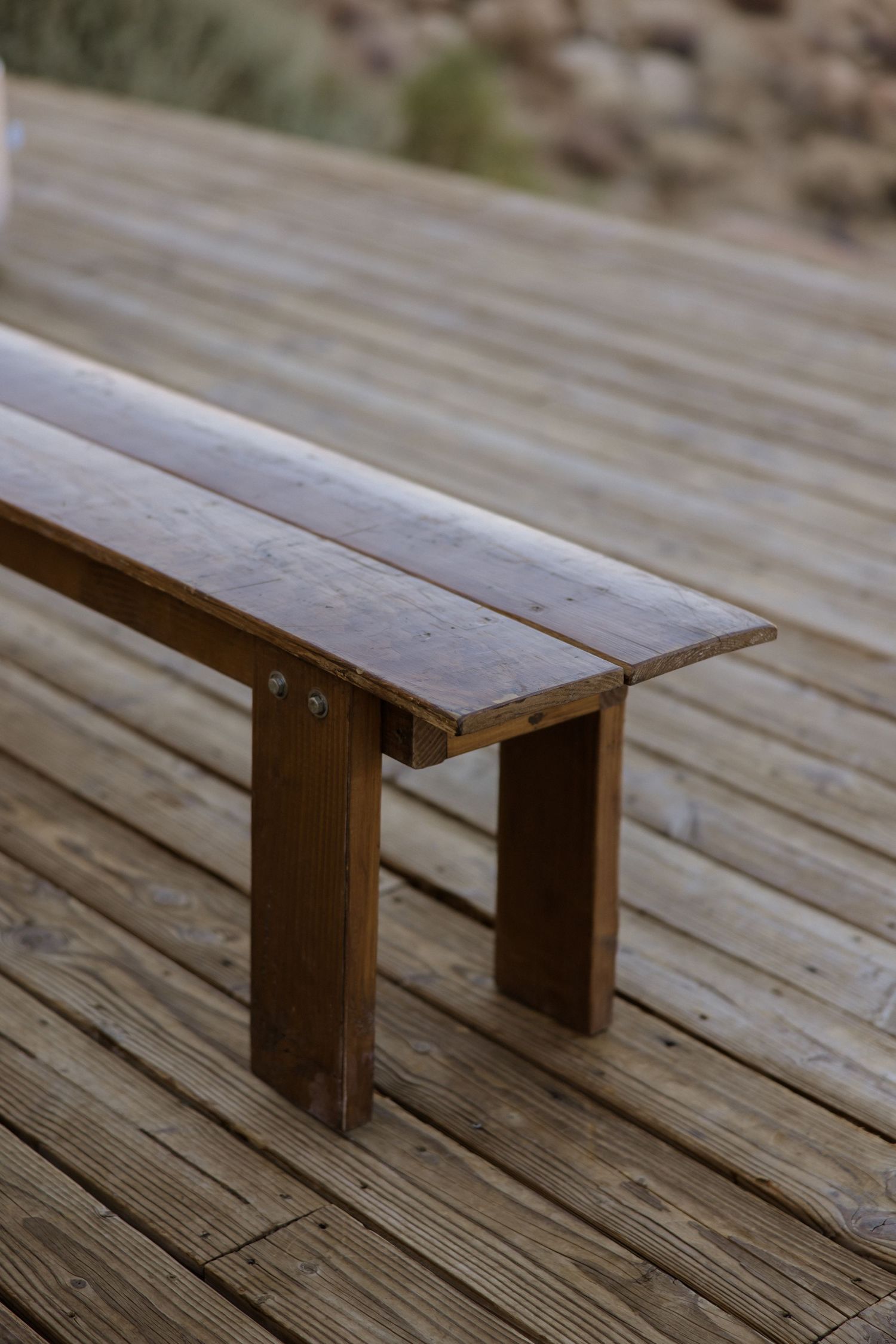 Progression of brown wooden bench from different angles on weathered deck boards.