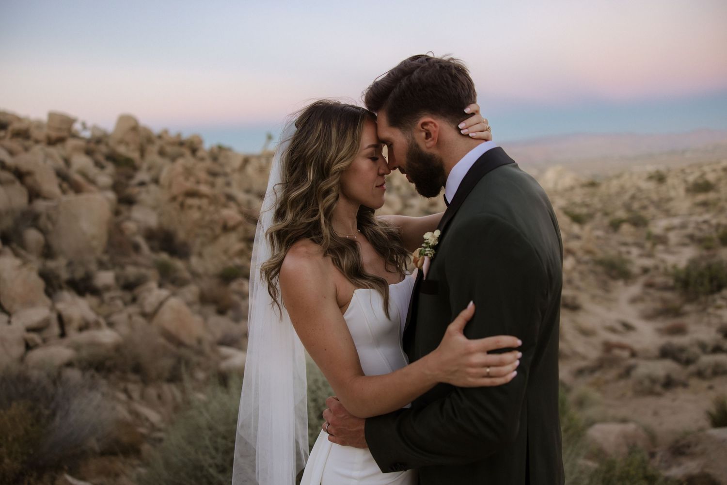 Romantic desert wedding photoshoot at Joshua Tree National Park during sunset with dreamy pink sky.
