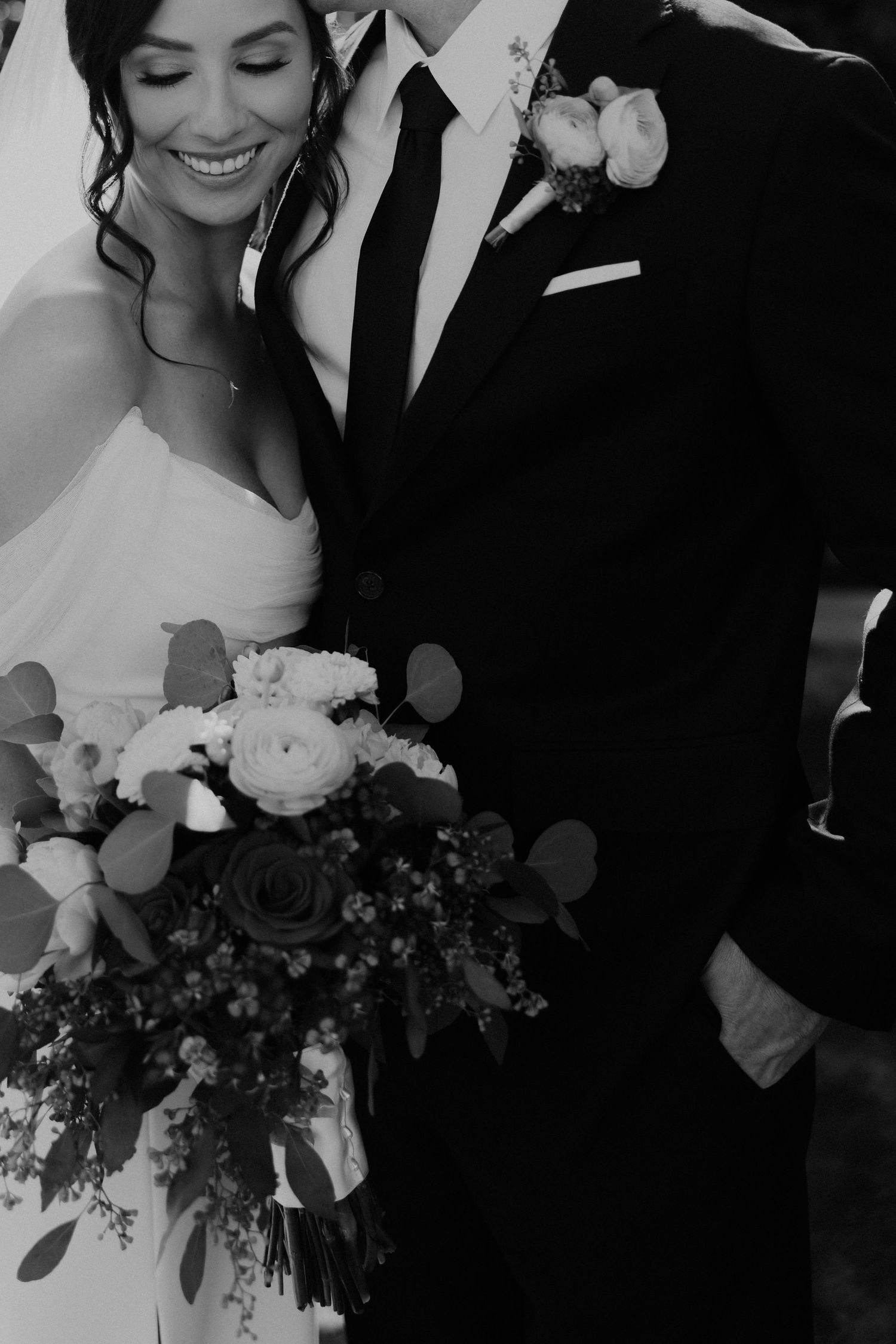 Black and white wedding portrait series showing romantic moments between a couple with beautiful floral bouquet details.