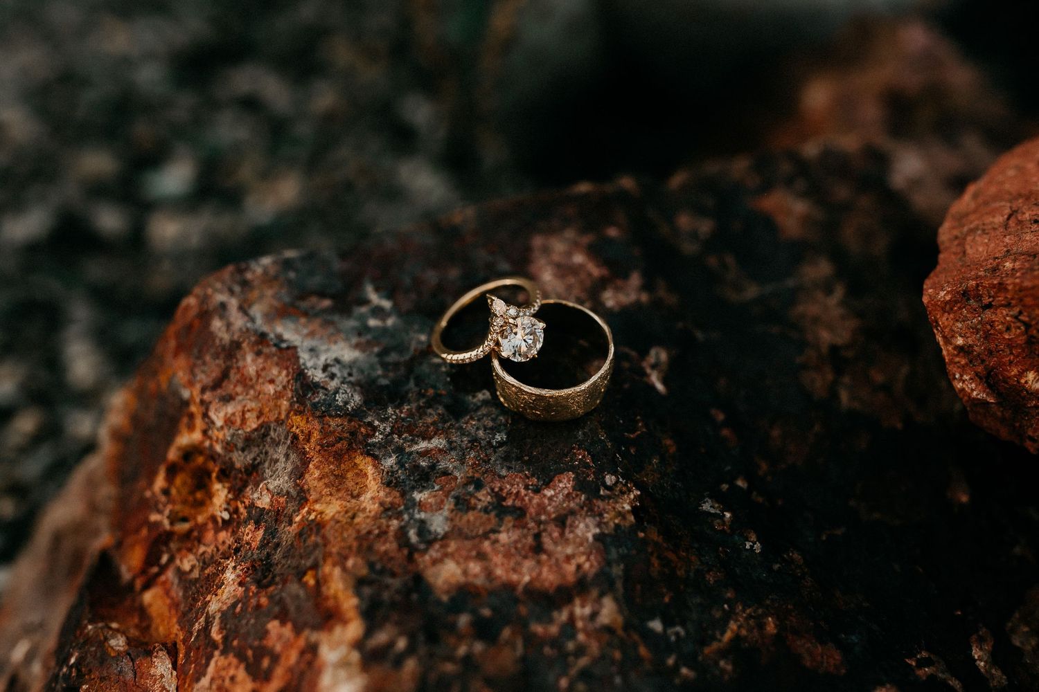 A macro close-up of several diamond rings resting on a textured brown stone surface.