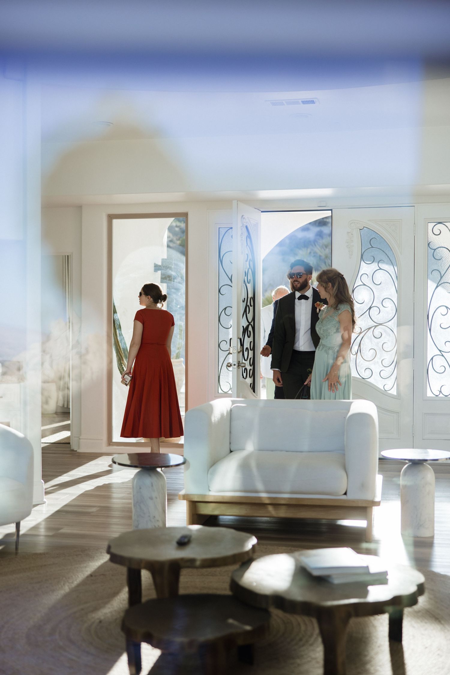 Elegant interior scene with decorative glass doors, white furniture and low wooden tables in a bright, modern space.