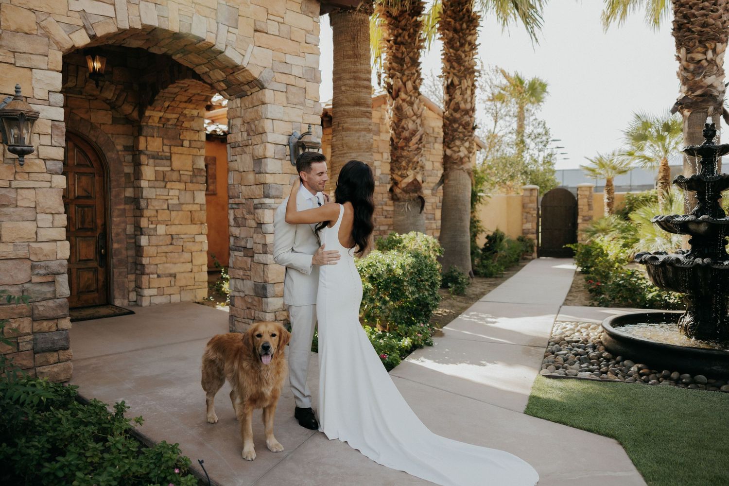 Bride and groom pose for elegant photos in a Mediterranean-style venue with stone arches and palm trees.