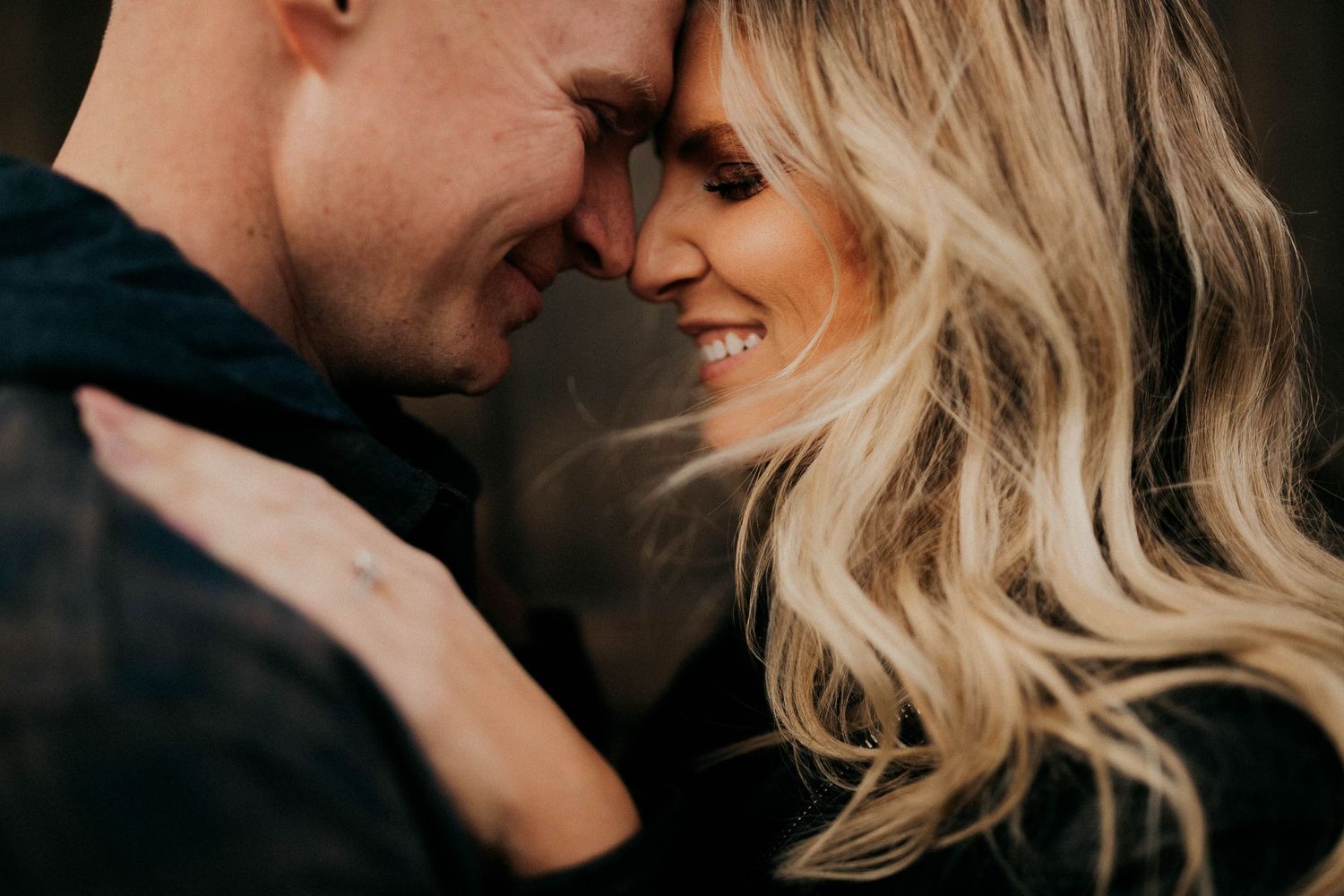 Romantic couple shares tender embrace while dancing at dusk in candid black and white photography series.