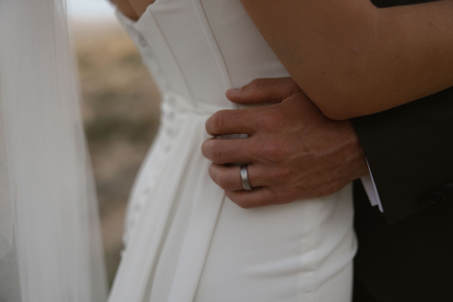 Newlyweds holding hands and embracing in their wedding attire during an intimate photo session.