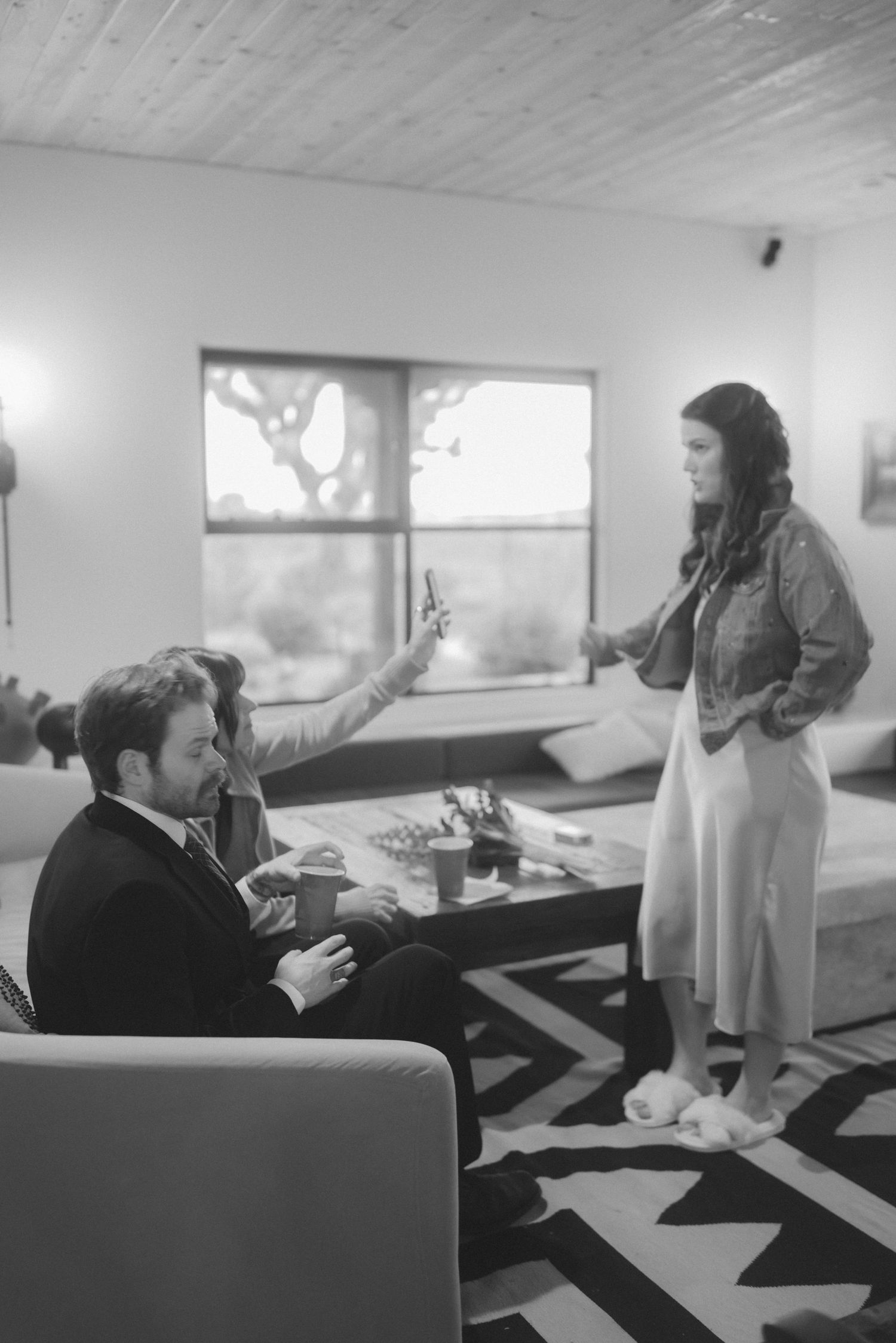 Black and white photo of bride and groom exchanging gifts indoors before desert elopement ceremony.