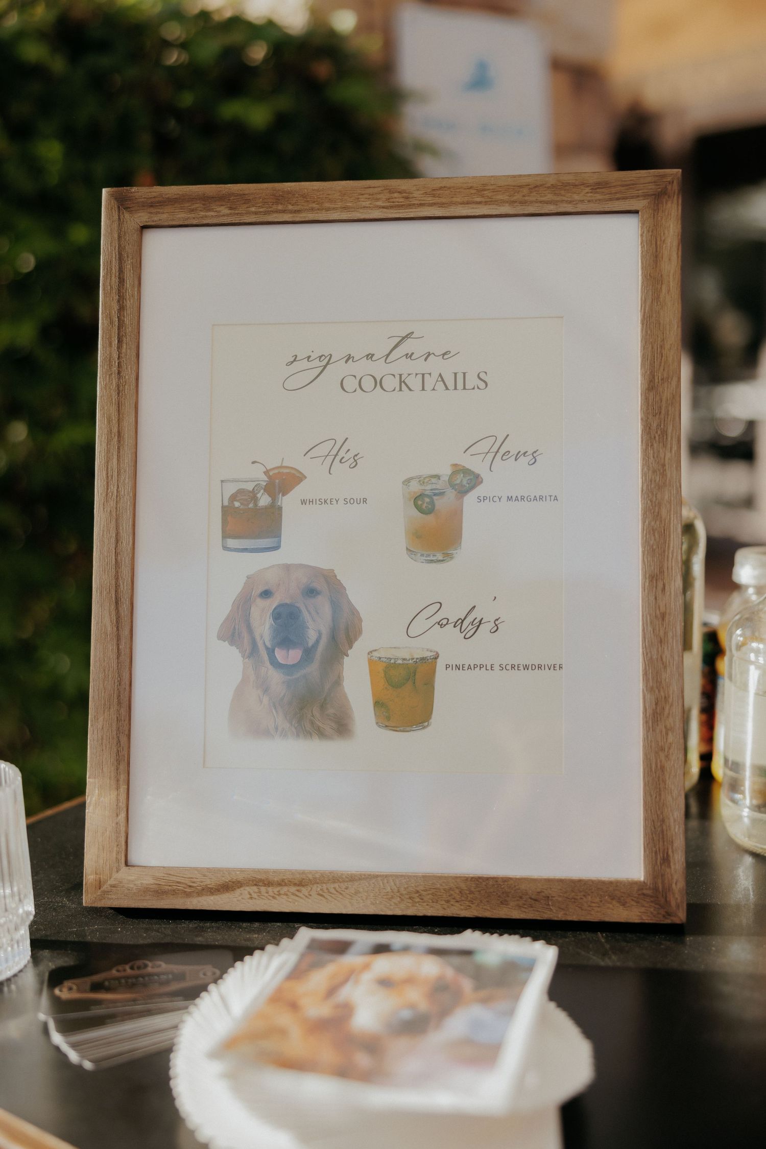 Collection of elegant cocktail menu signs in wooden frames displayed at a reception or event.