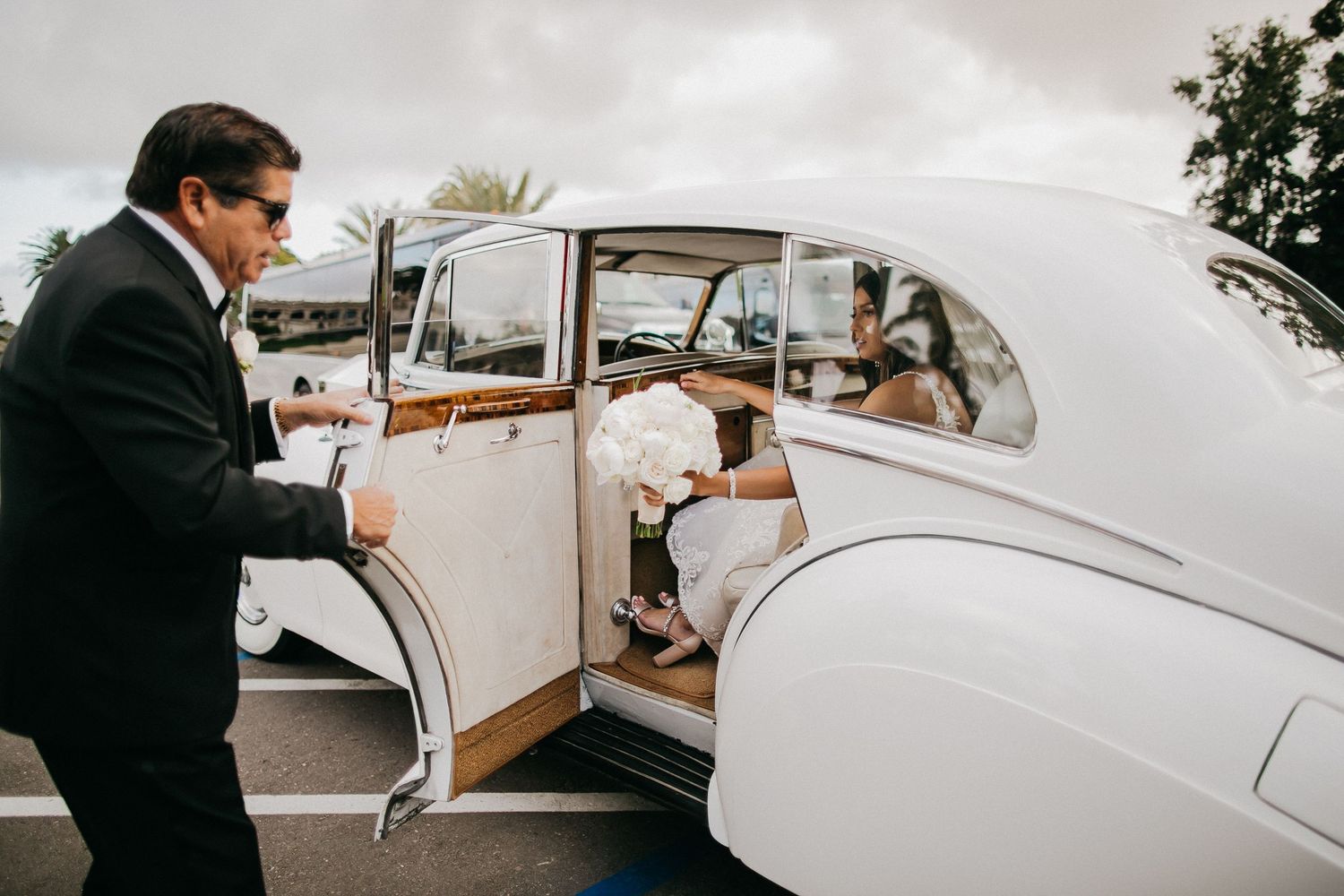 Classic white vintage wedding car with elegant details being photographed.