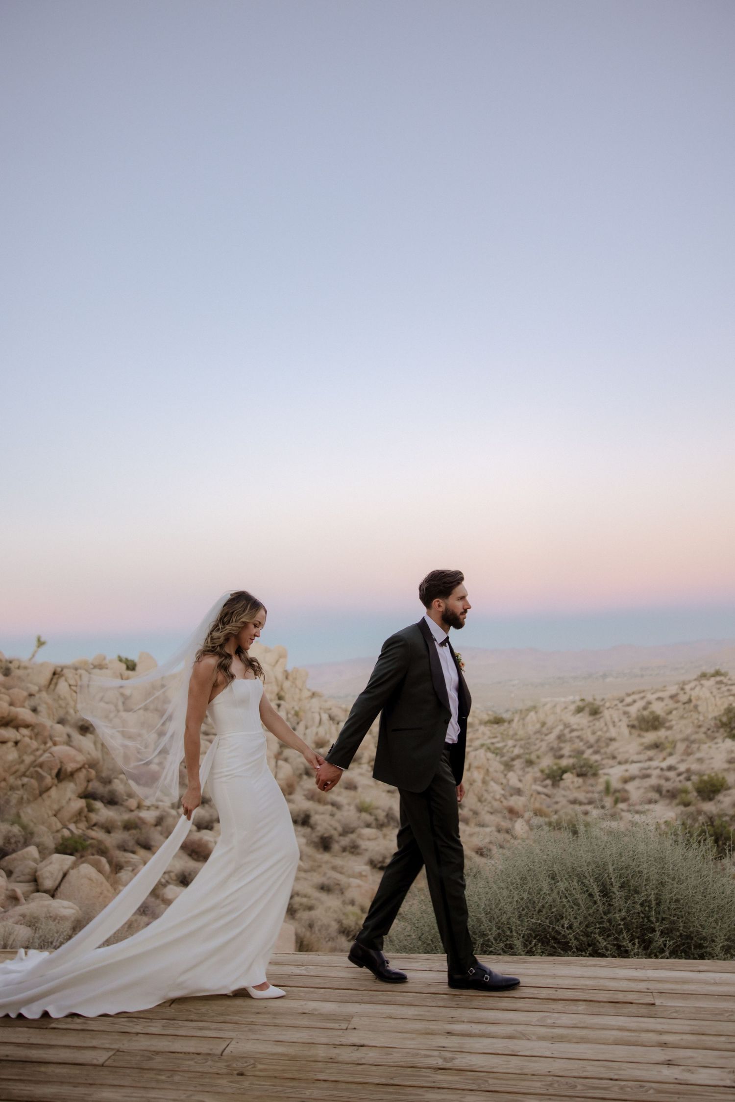 A couple in wedding attire poses in a sequence of romantic photos on a wooden deck against a desert landscape at sunset.