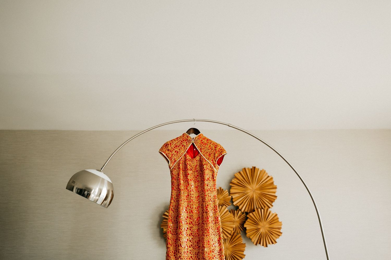 Orange floral dress with matching paper flowers arranged in a minimalist flat lay composition against beige background.