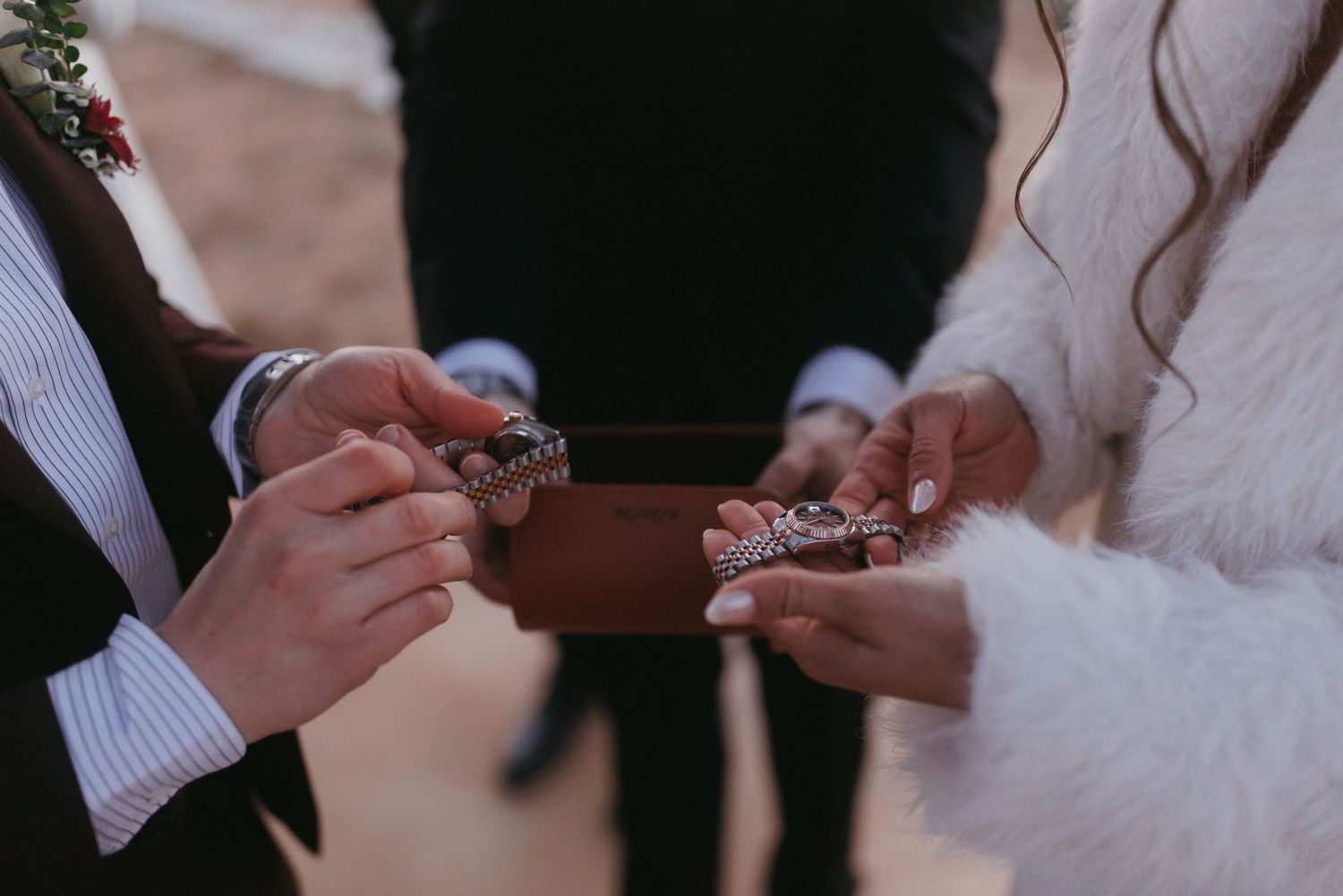 A couple exchanges ornate wedding rings during an outdoor desert ceremony.