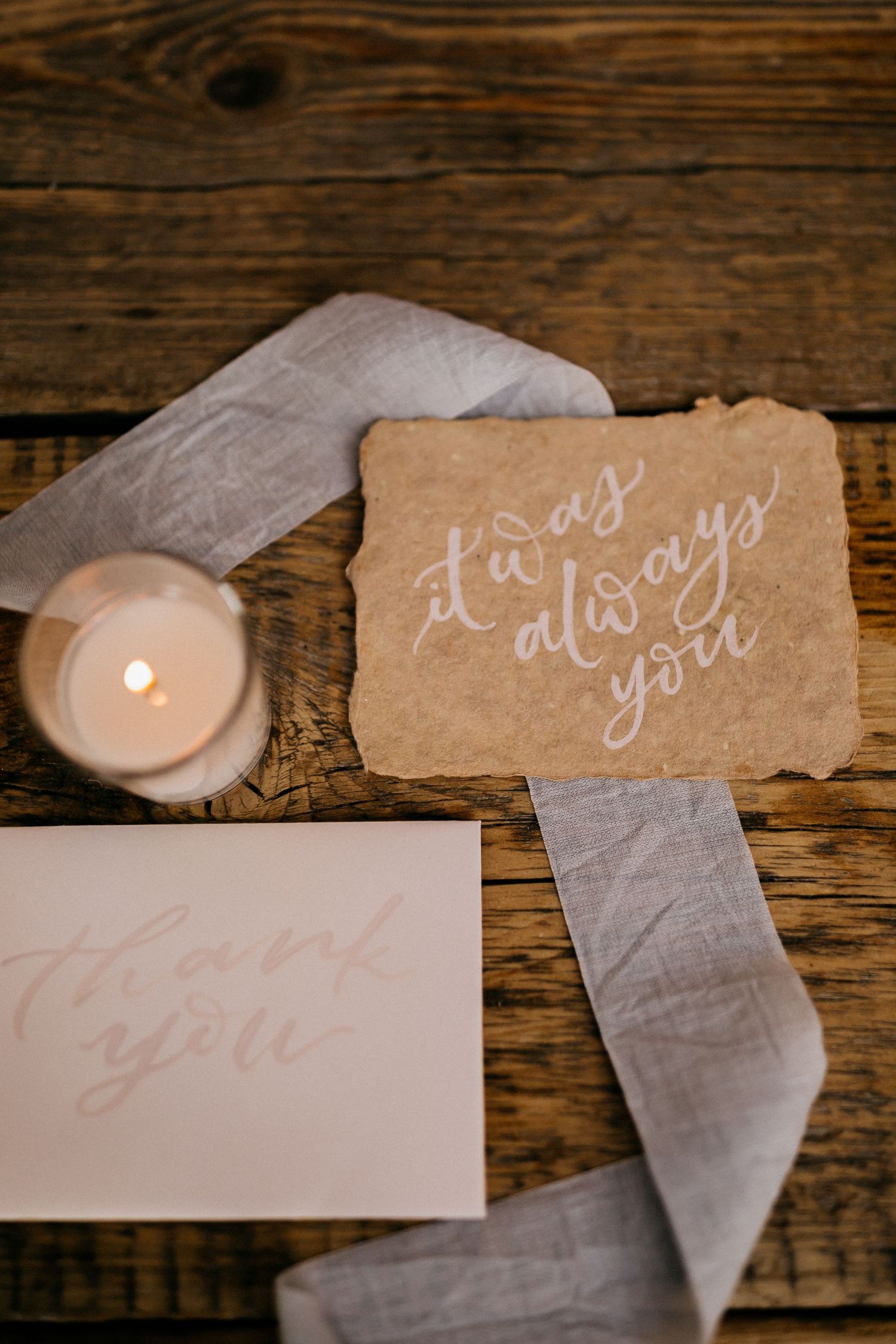 Delicate handwritten wedding cards and notes arranged on a rustic wooden background.