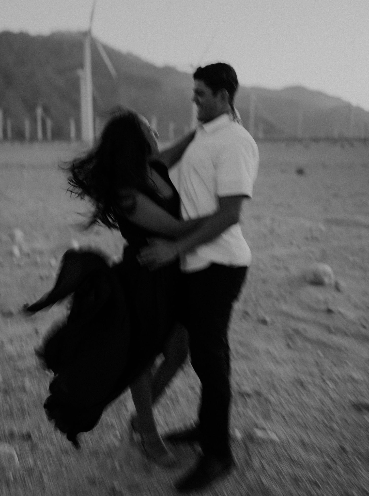 Black and white sequence showing a couple spinning together joyfully in an embrace outdoors.