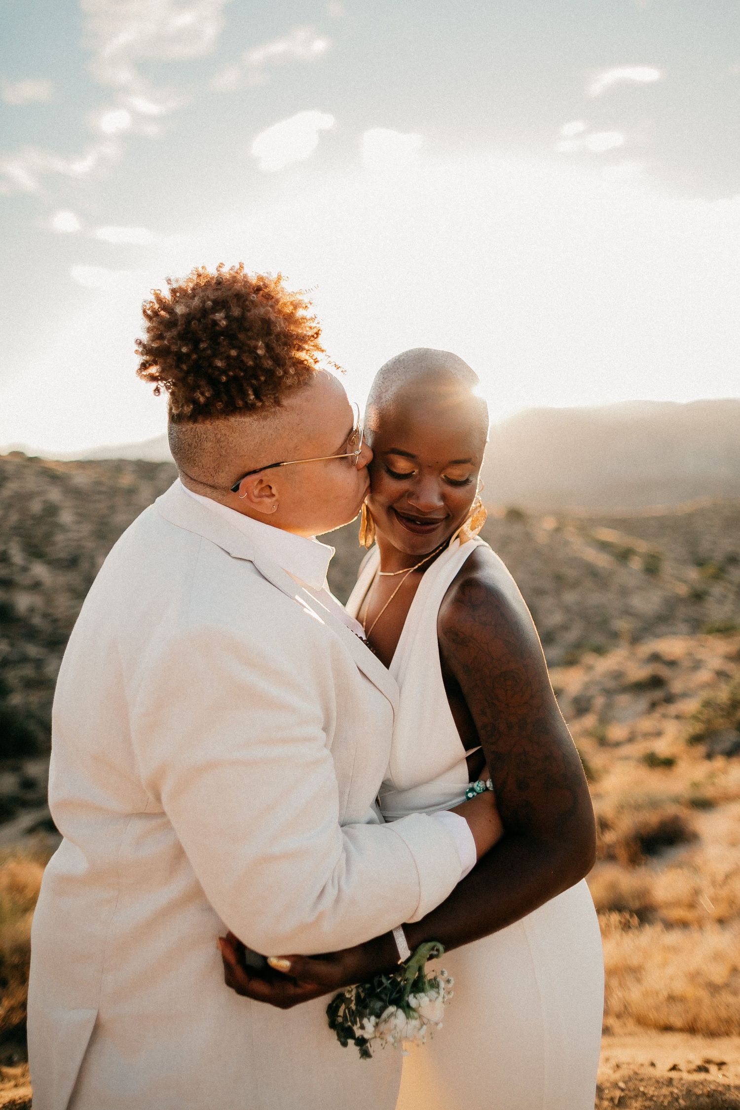 Intimate wedding couple embracing during golden hour in desert landscape.