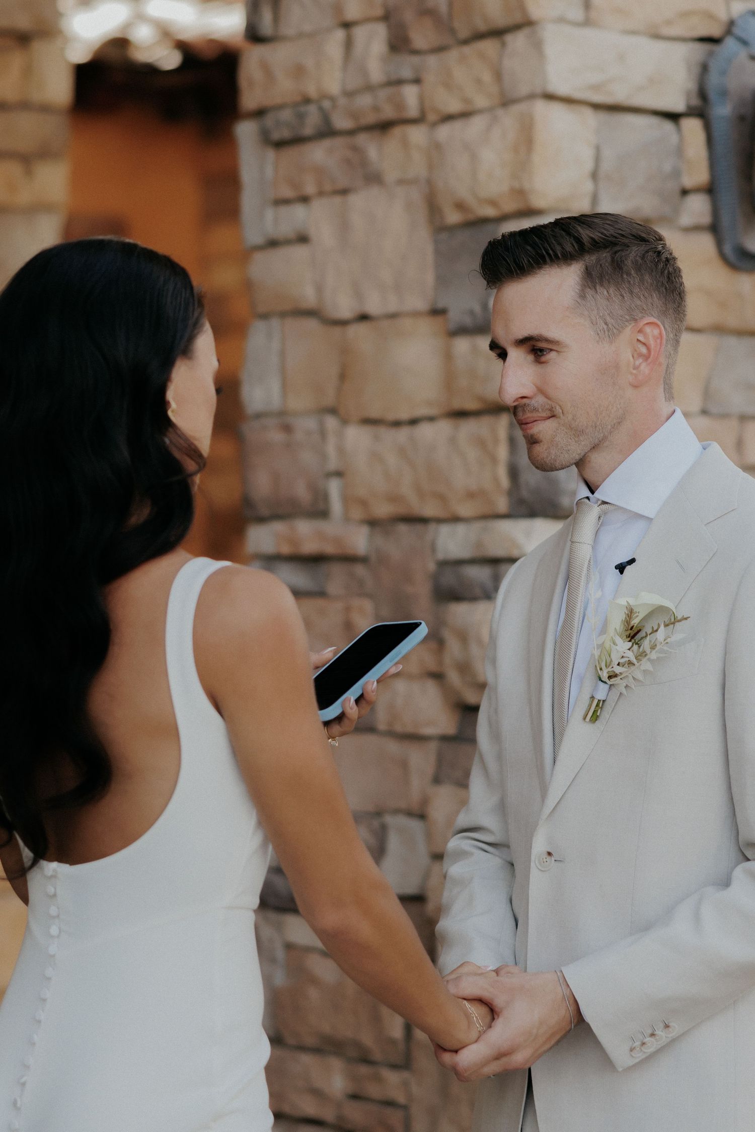 During a wedding first look moment, the couple exchanges looks against a rustic stone wall backdrop.