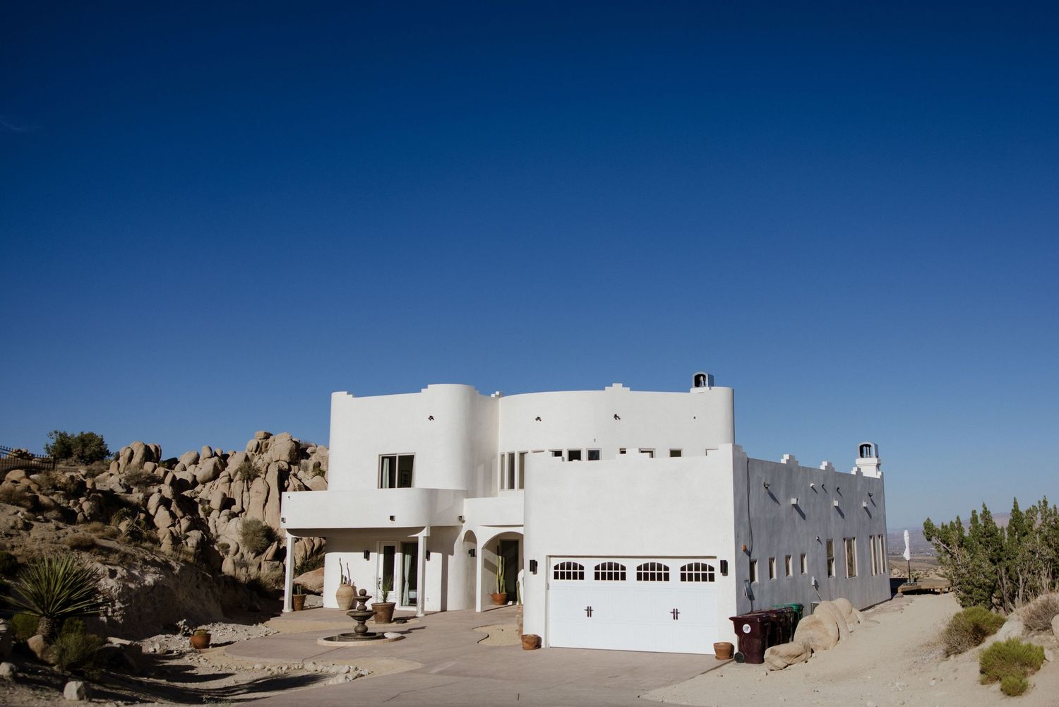 Traditional white adobe buildings dot a stark desert landscape against bright blue skies in New Mexico.