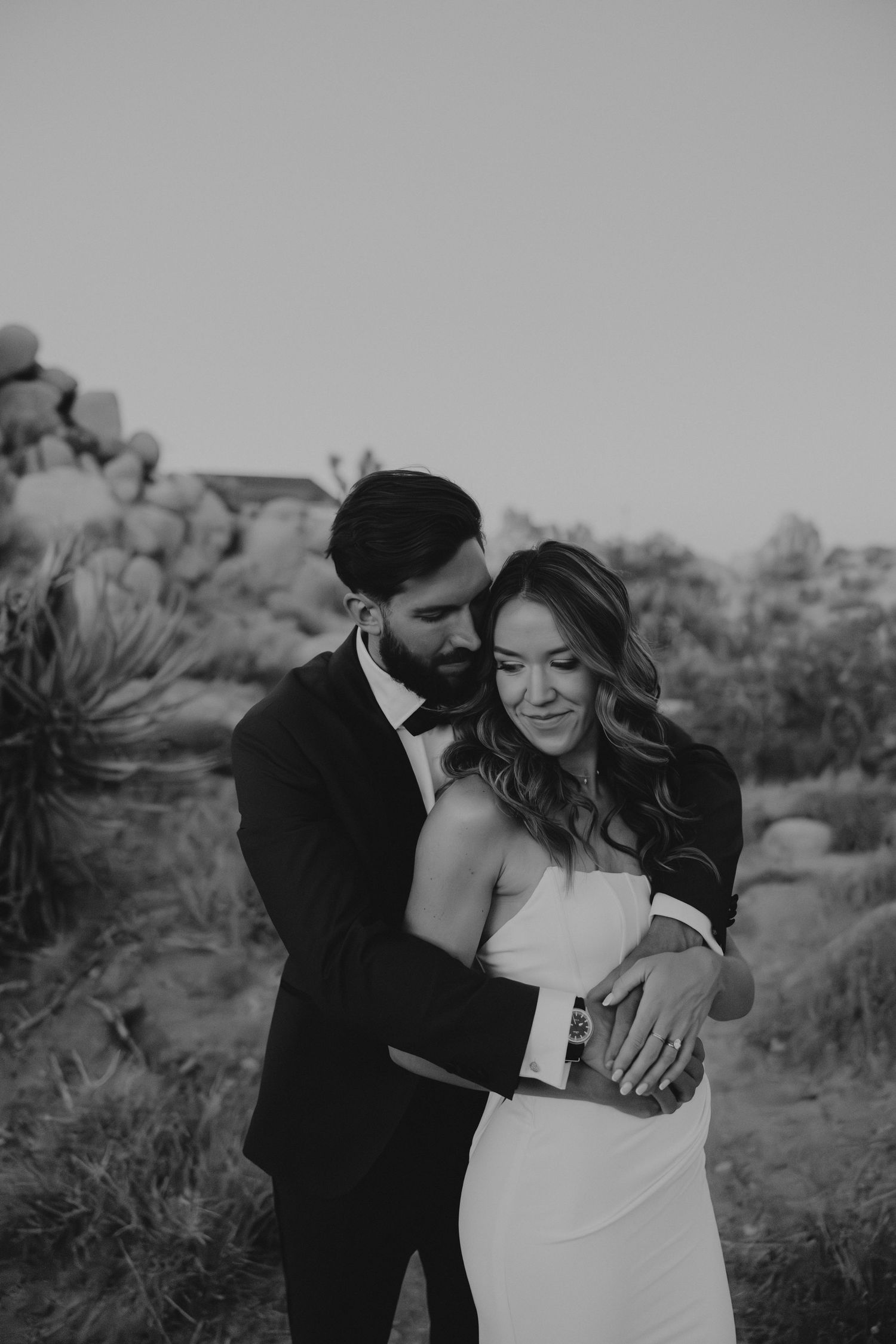 Black and white photo of a romantic moment between a couple in desert landscape with Joshua trees.