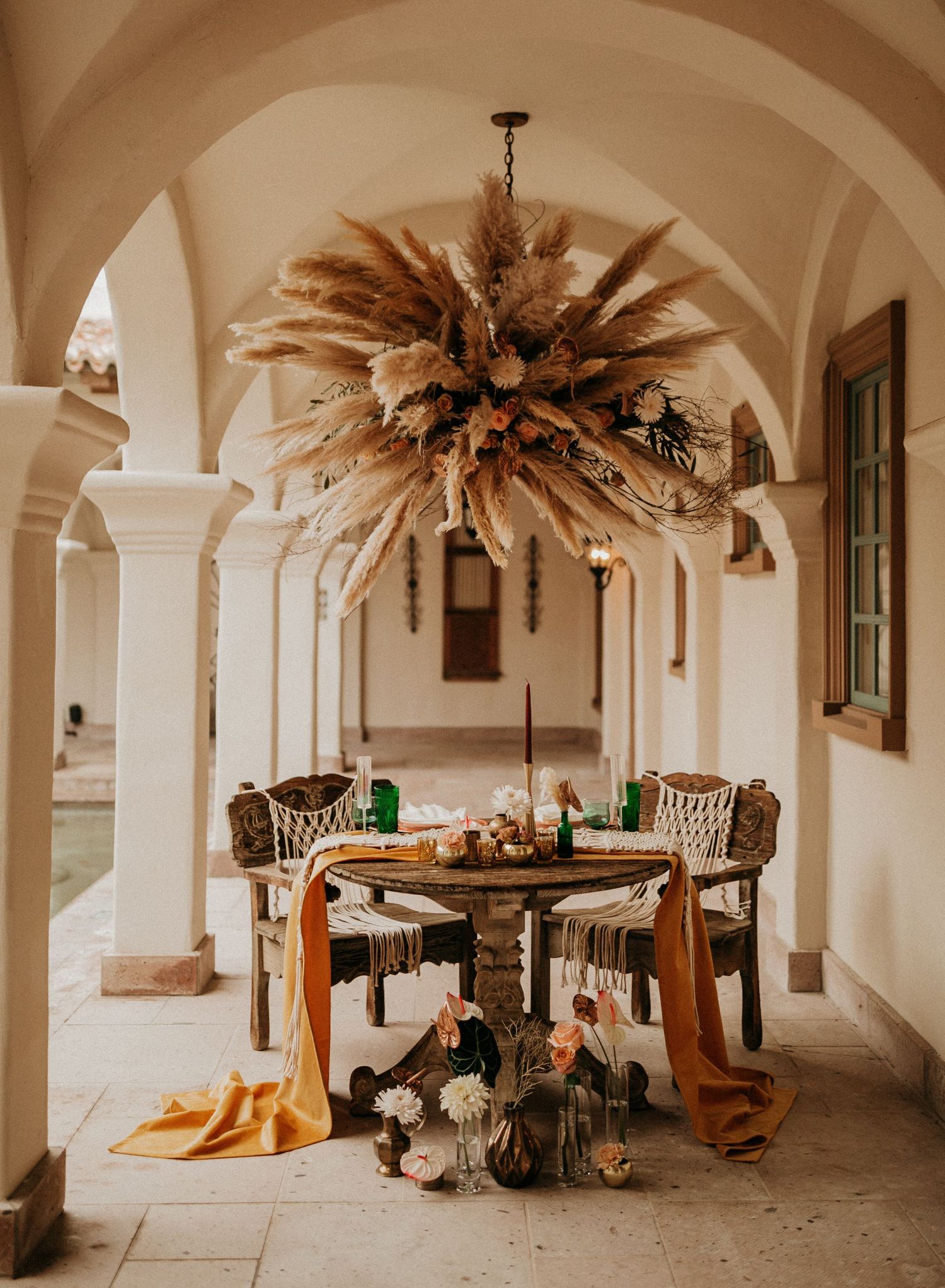 Elegant arched colonnade hallway in a historic building with ornate chandeliers and antique furniture.
