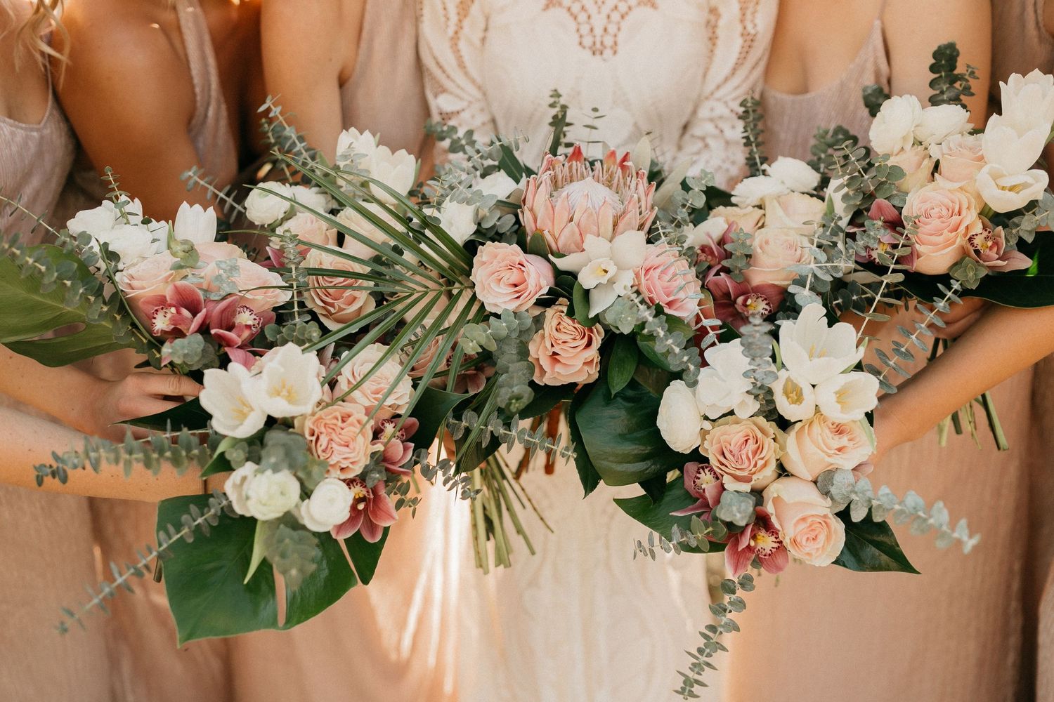 A row of elegant peach and white wedding bouquets with roses and mixed blooms arranged on a table.
