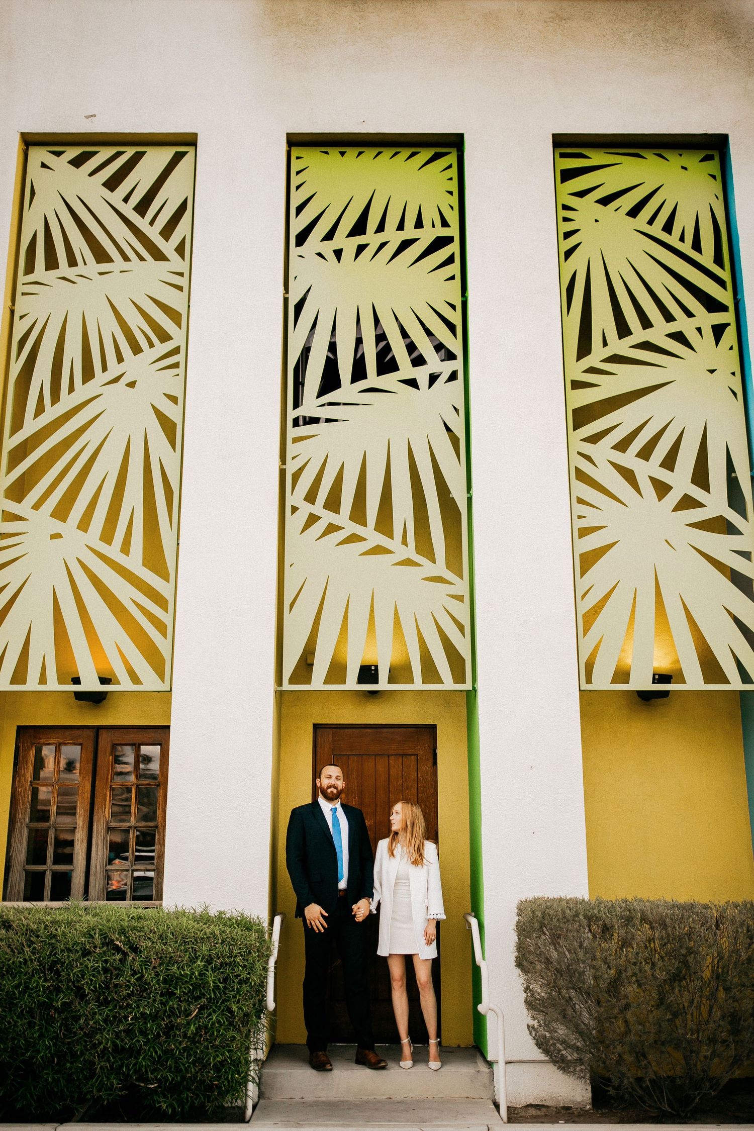 Art deco style palm frond cutouts decorate the wall of a Spanish colonial building.