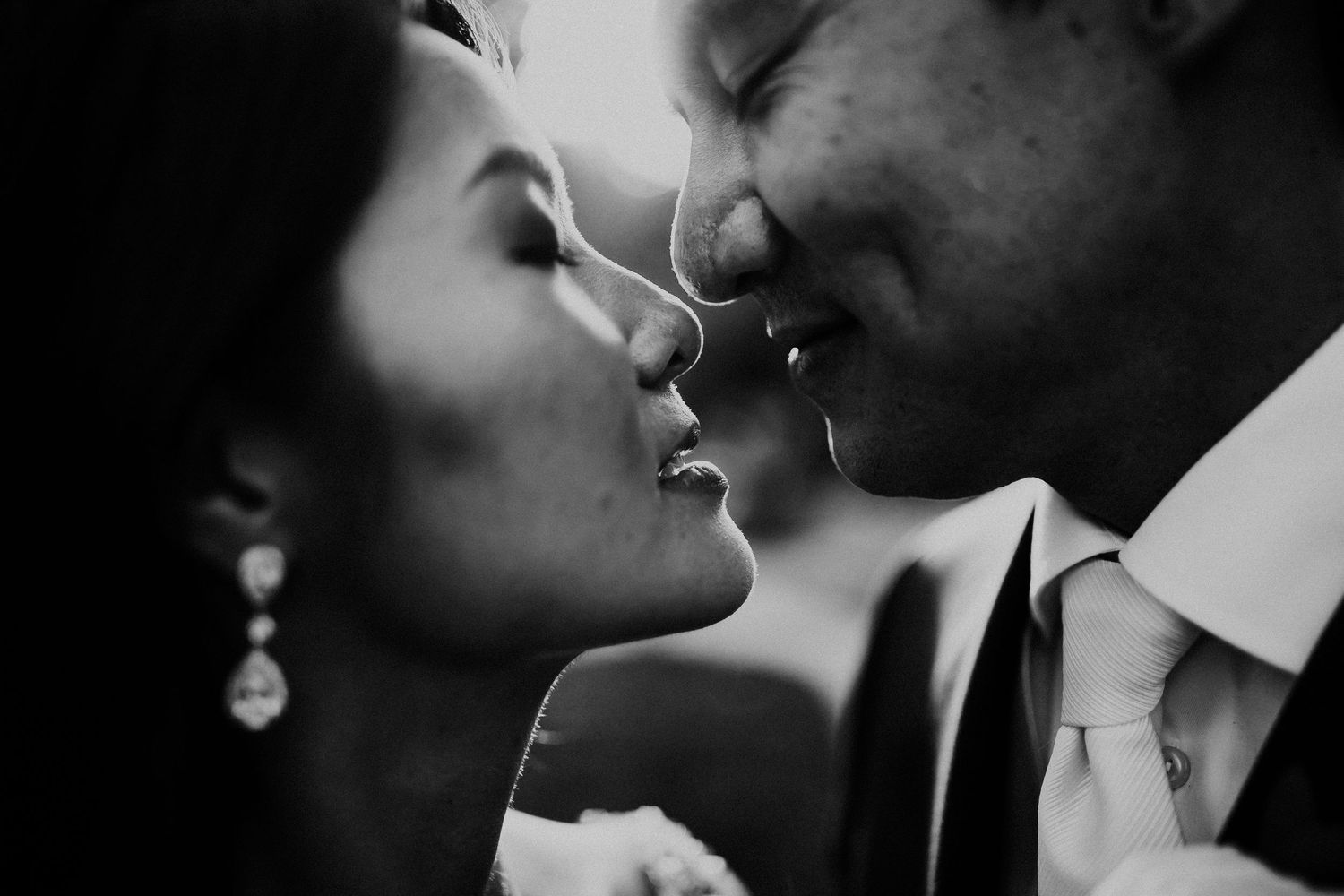 Romantic black and white close-up silhouette showing an intimate couple sharing a tender kiss.