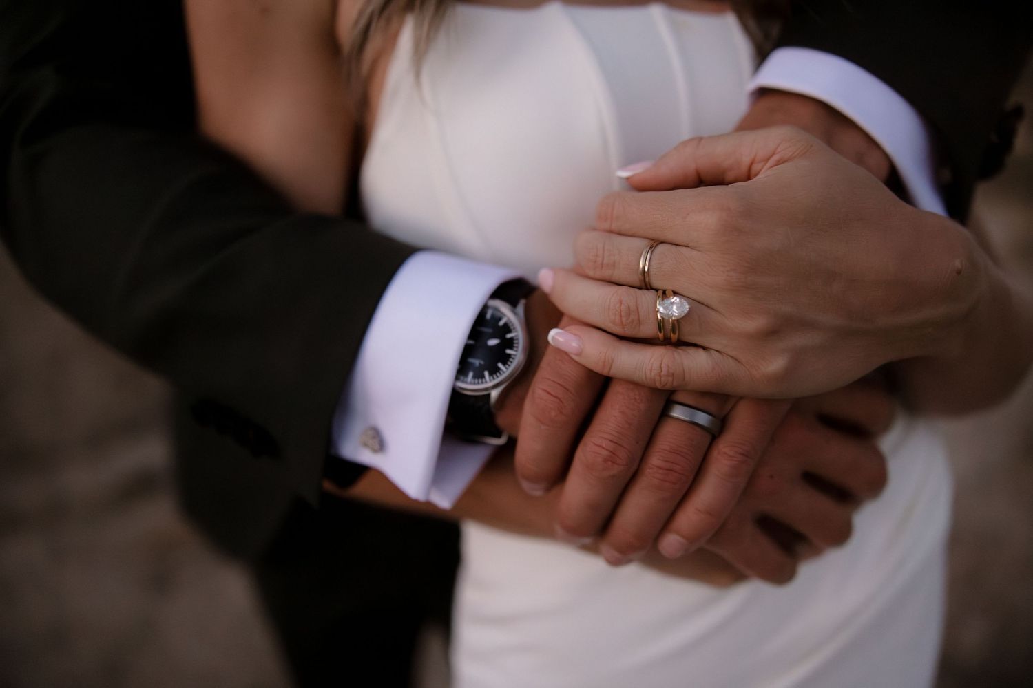 A series of hands wearing elegant wedding rings shown in different close-up angles against a dark background.