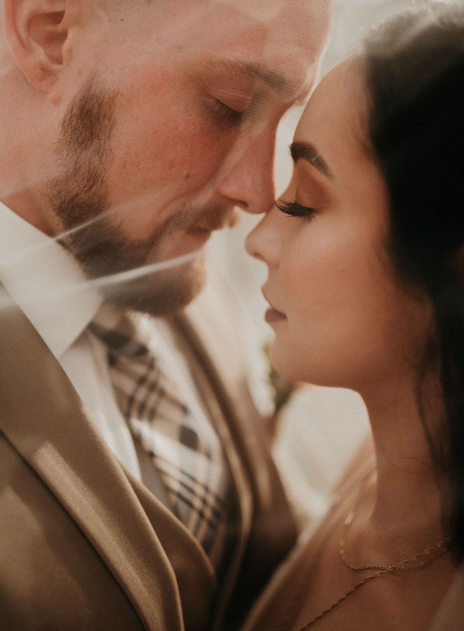 A romantic wedding portrait captured in warm, dreamy lighting with the couple in an intimate close-up moment.