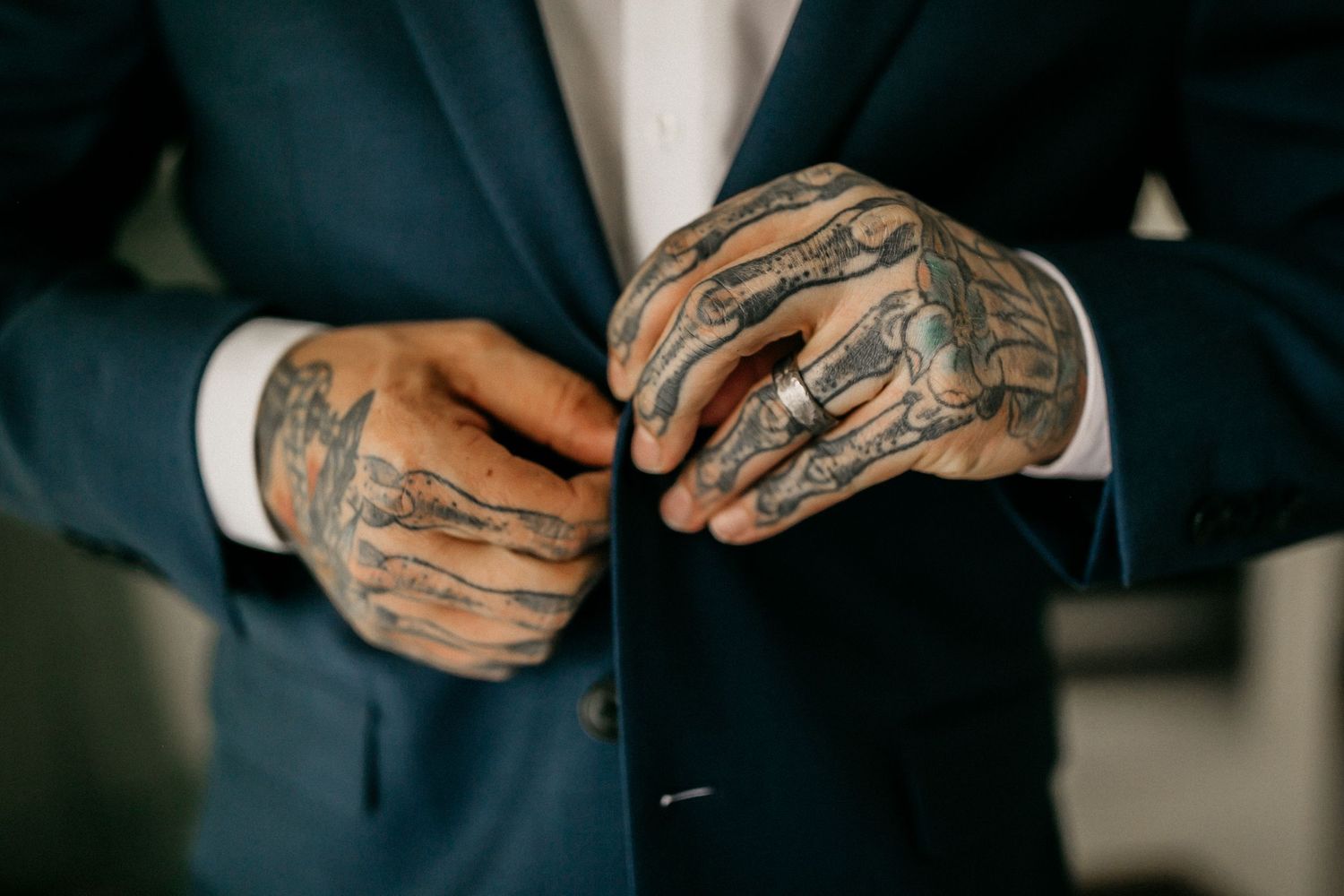 Detail shots of hands with tattoos and jewelry against a dark background.