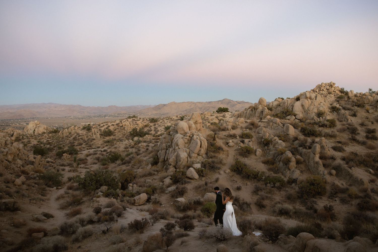 Expansive desert mountain landscape bathed in golden sunlight with rugged rock formations stretching to the horizon.