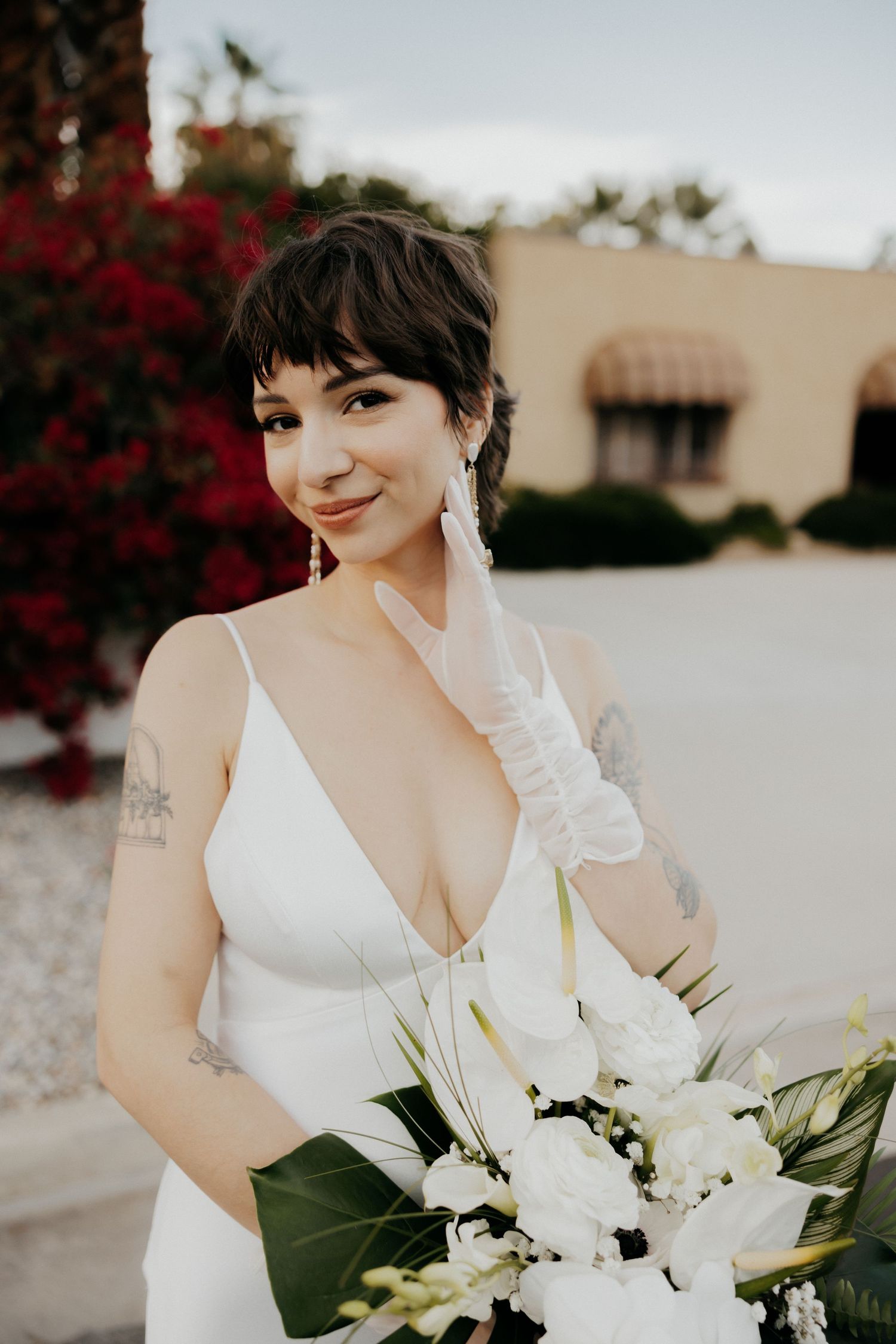 A bride wearing a white dress holds an elegant bouquet of white lilies and flowers.