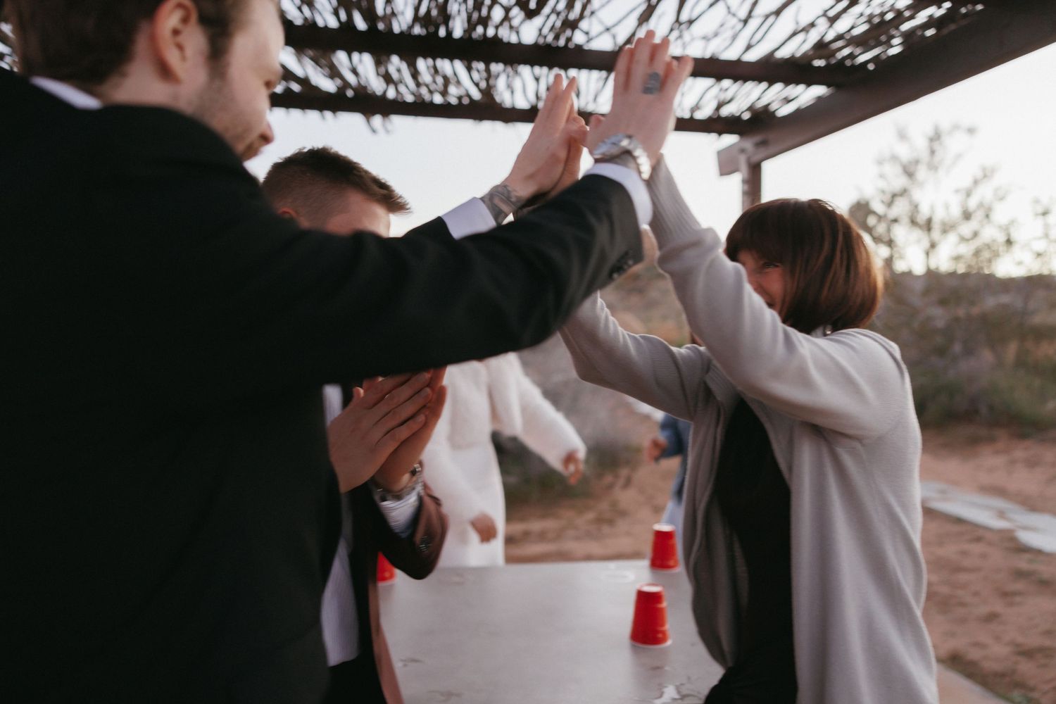 Wedding guests celebrate with high fives at outdoor desert reception.