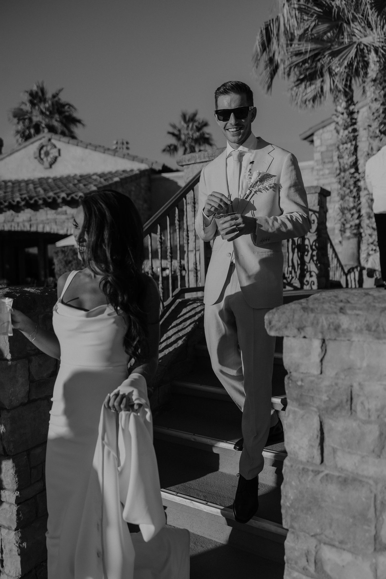 A series of black and white photographs showing a couple in formal attire posing together outdoors near a stone wall.