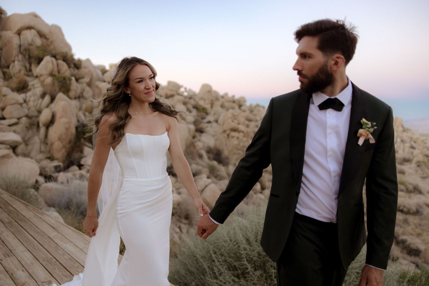 Romantic wedding couple posing in front of desert rocks during sunset at Joshua Tree National Park.