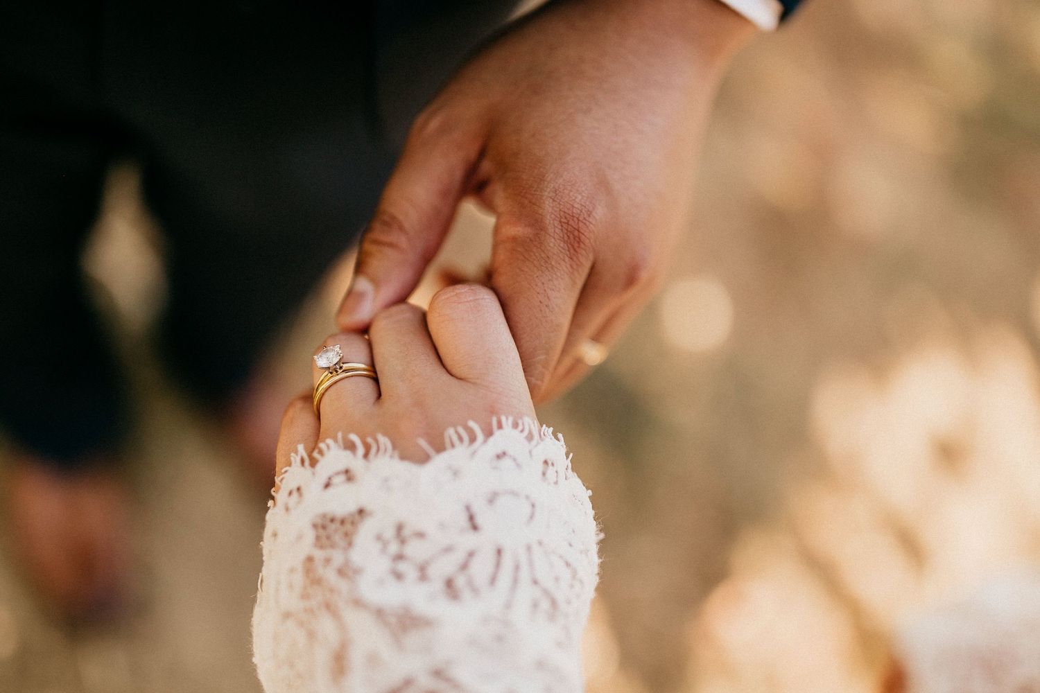 Two hands carefully tear a piece of soft white paper into delicate shreds against a warm sunlit background.