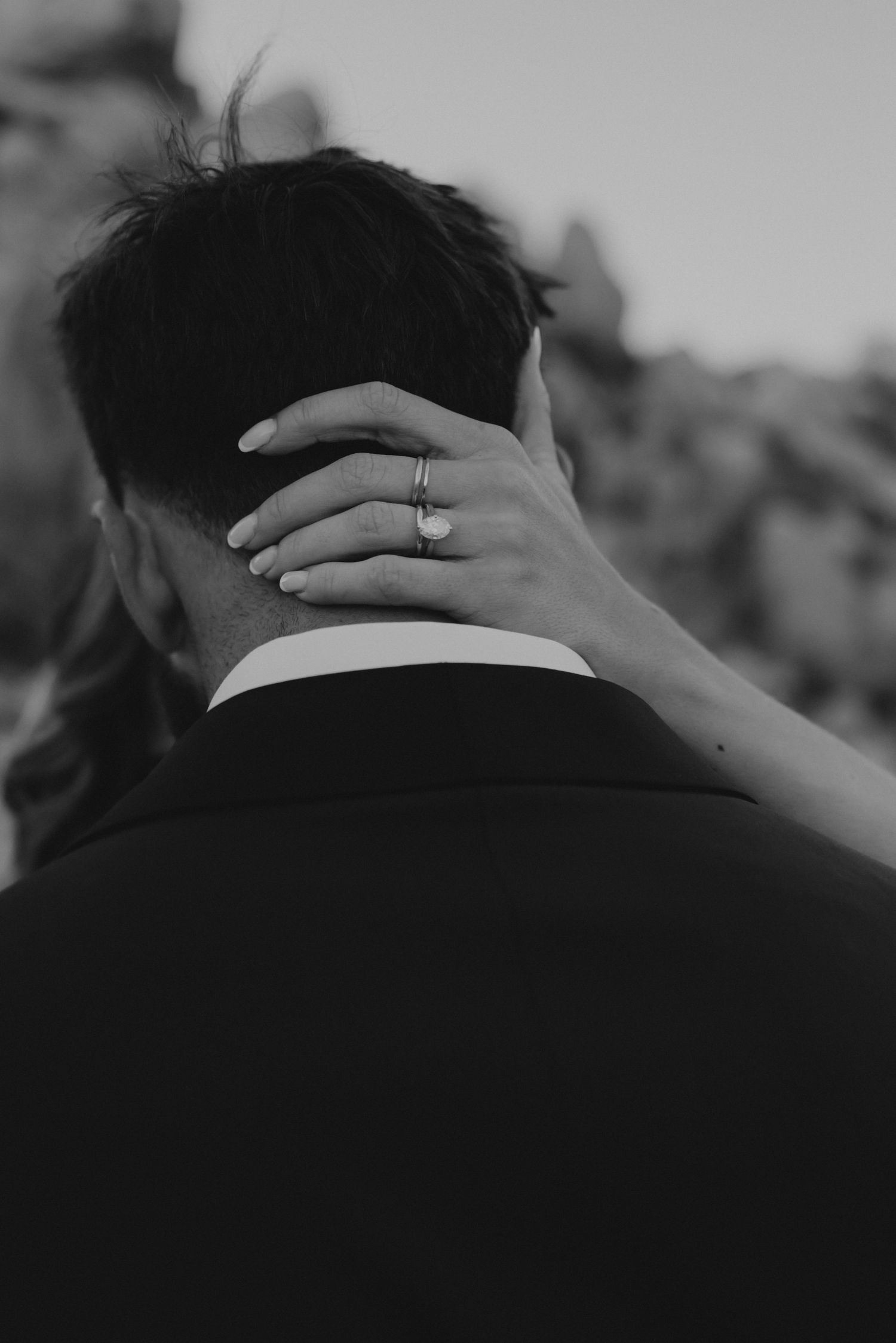 Elegant black and white close-up of hands gently embracing during a romantic wedding moment.