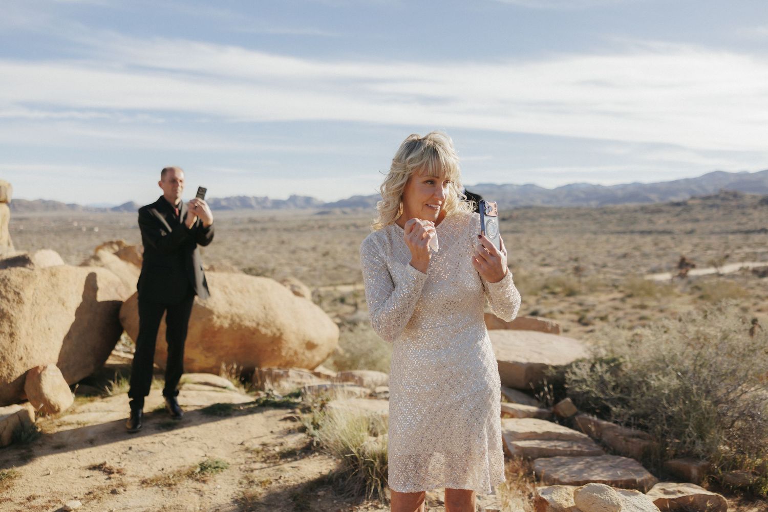 Emotional bride wiping tears in a white lace dress during an outdoor desert elopement ceremony.