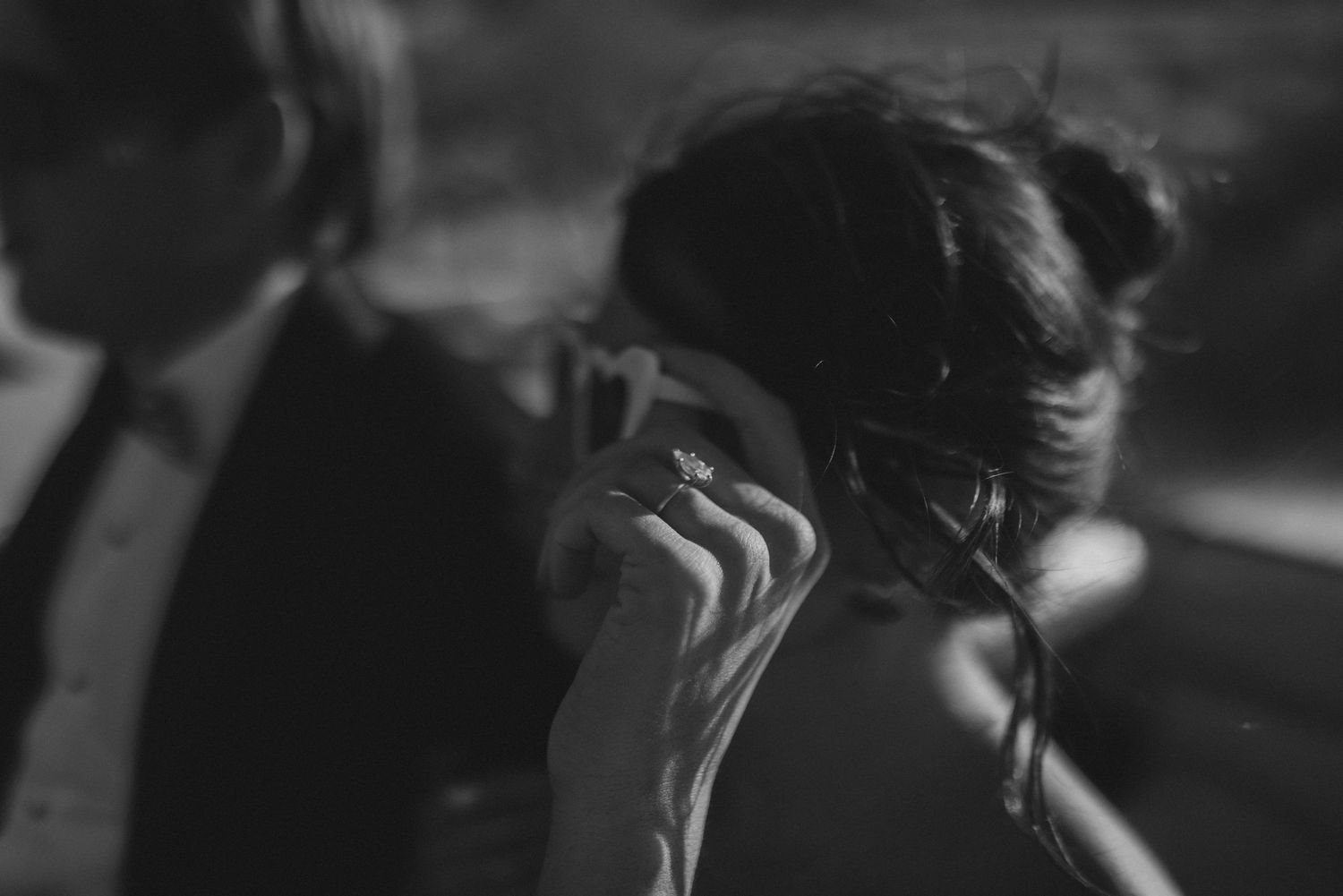 Emotional bride wiping tears while wearing her engagement ring on her wedding day in a black and white photo.